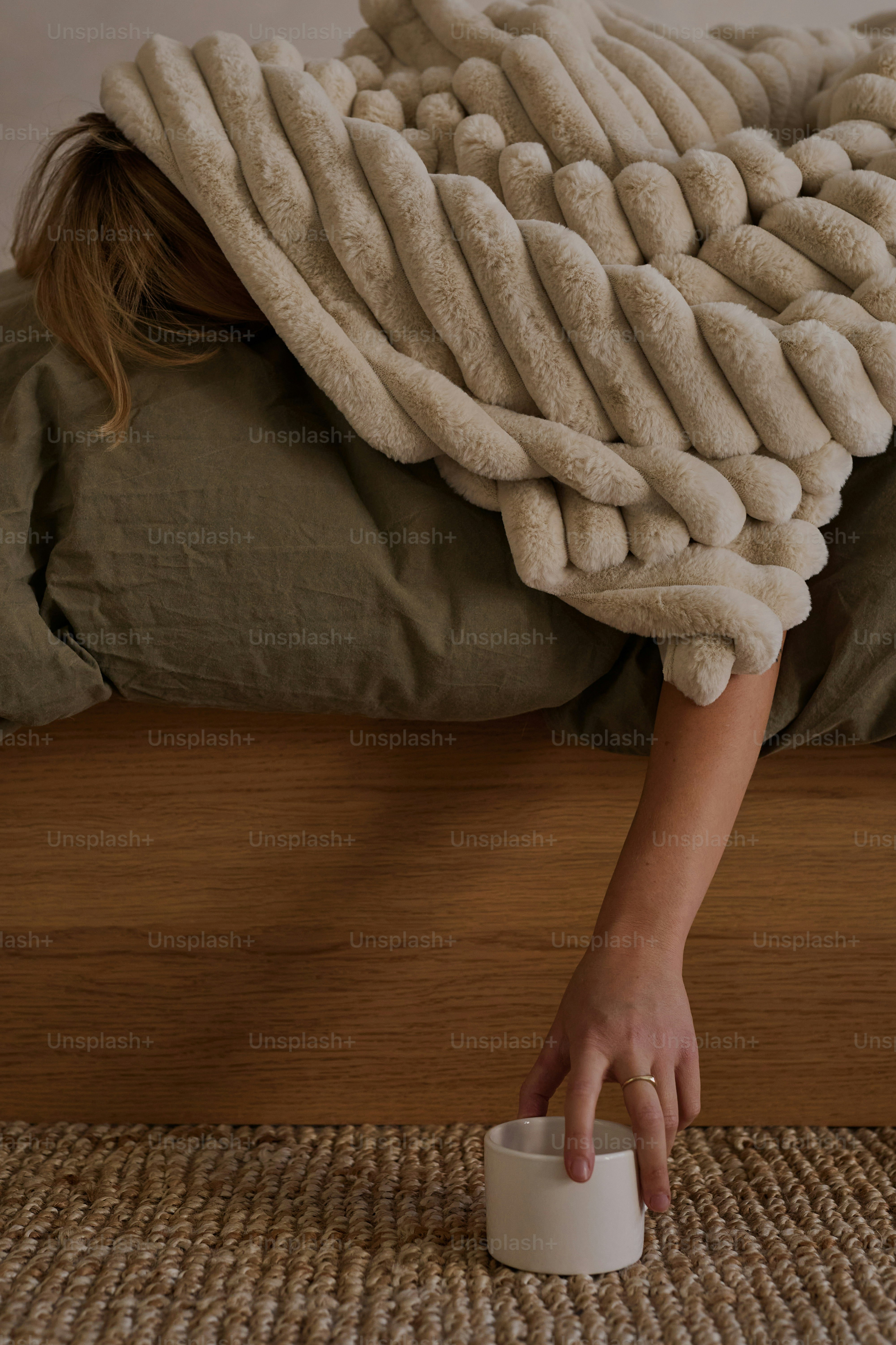 Woman reaching for cup from bed