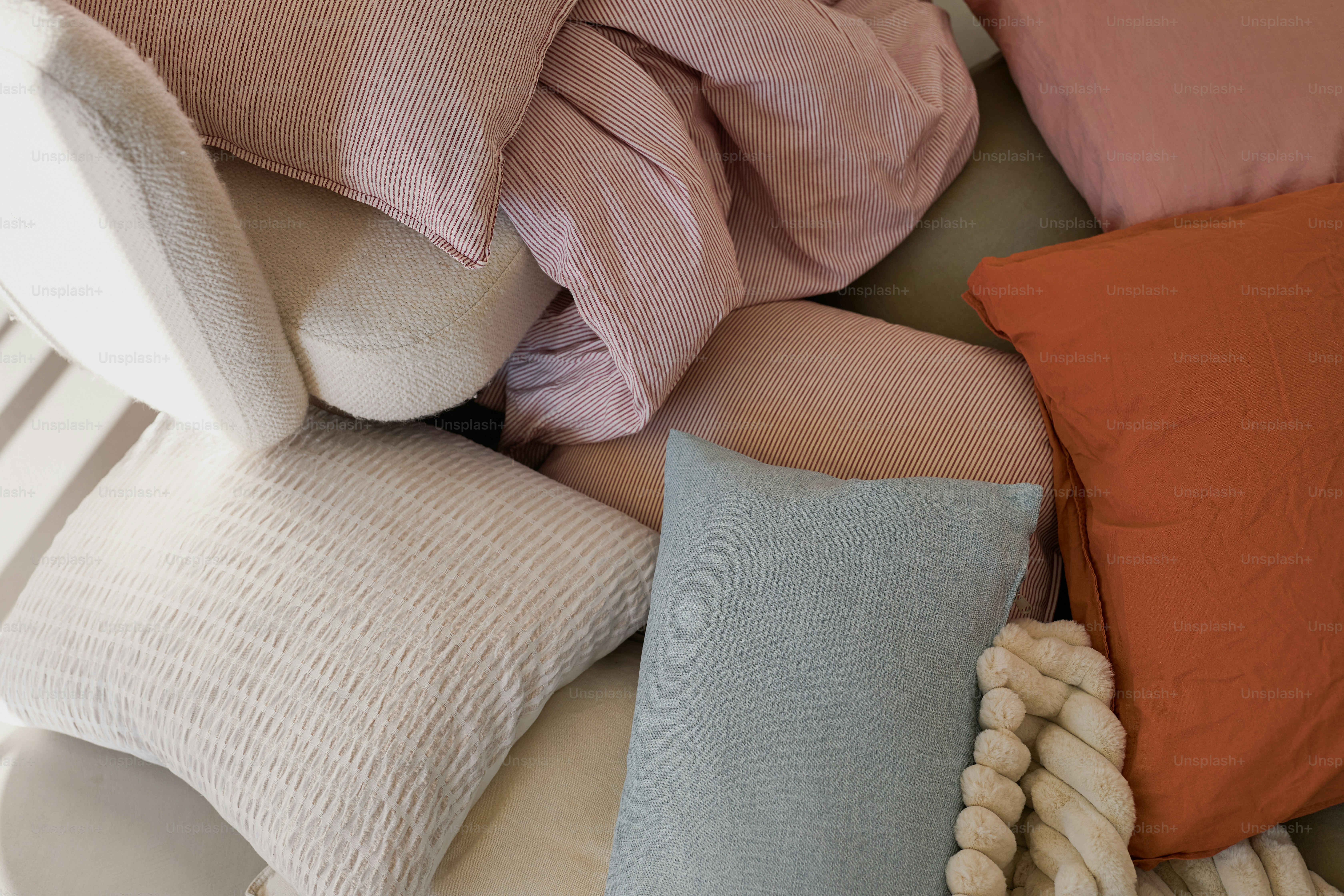 Pile of soft pillows and blankets in various colors.