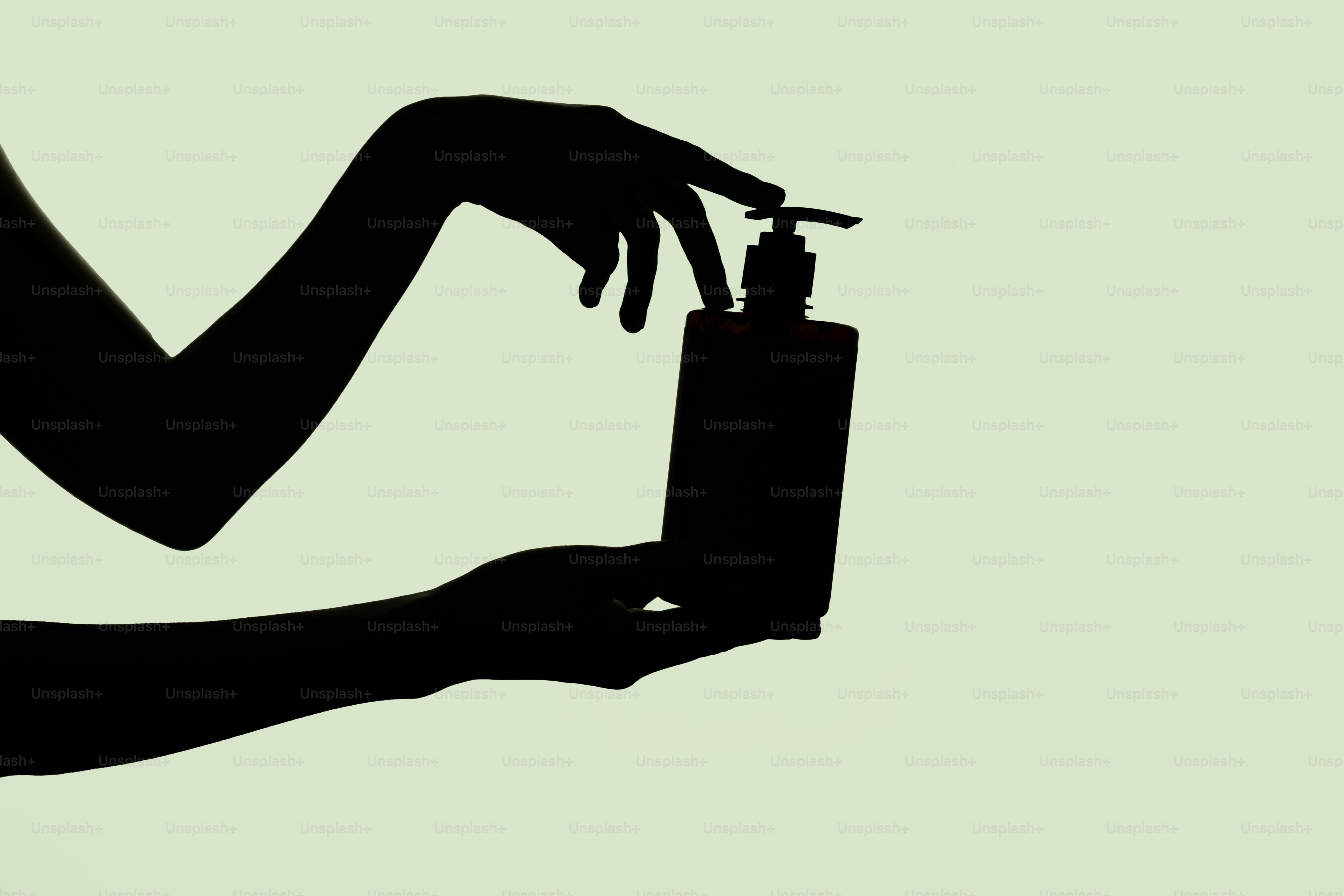 Silhueta de mãos segurando e pressionando um frasco dispensador