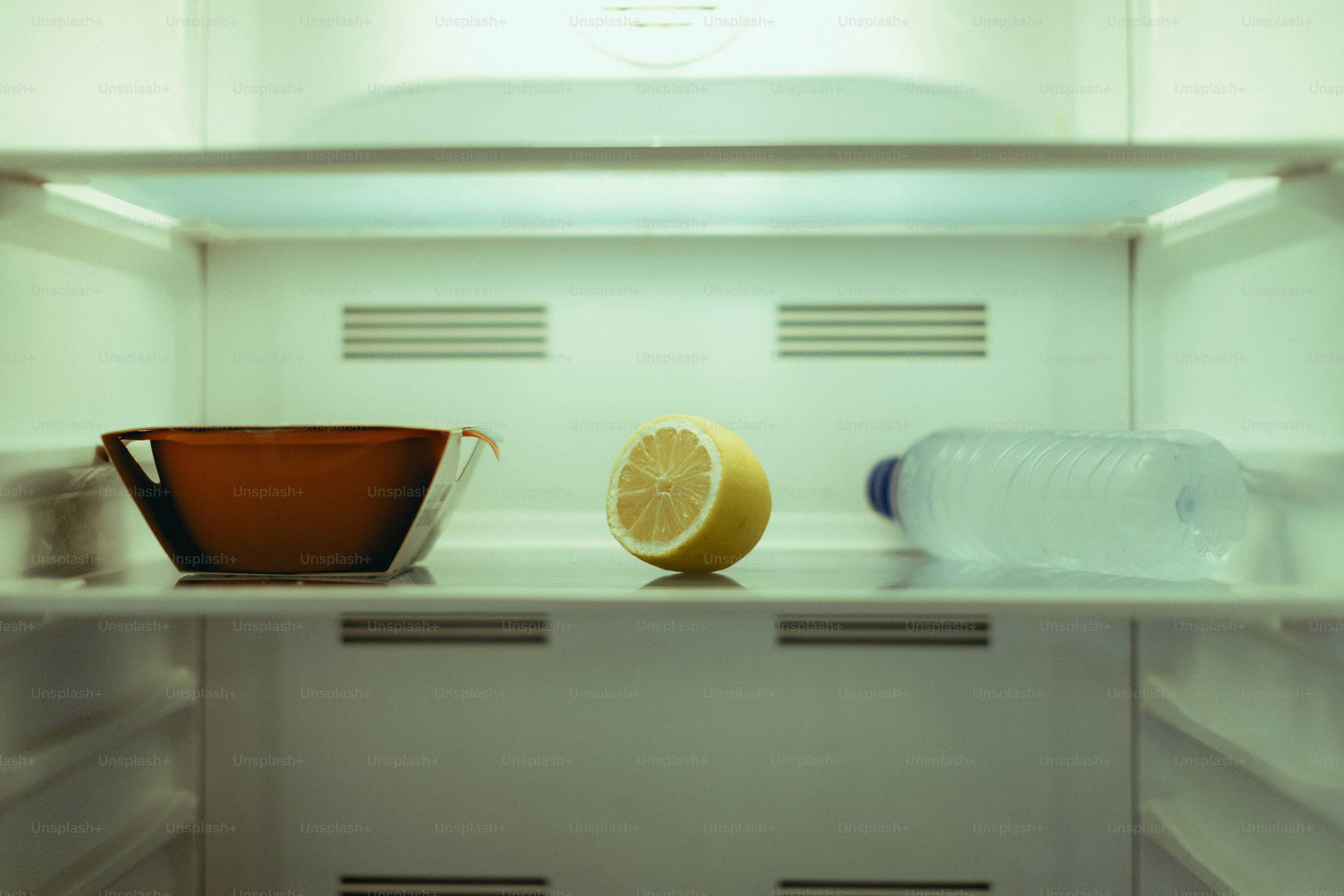 Leere den Kühlschrank mit einer Schüssel, Zitrone und Wasser.
