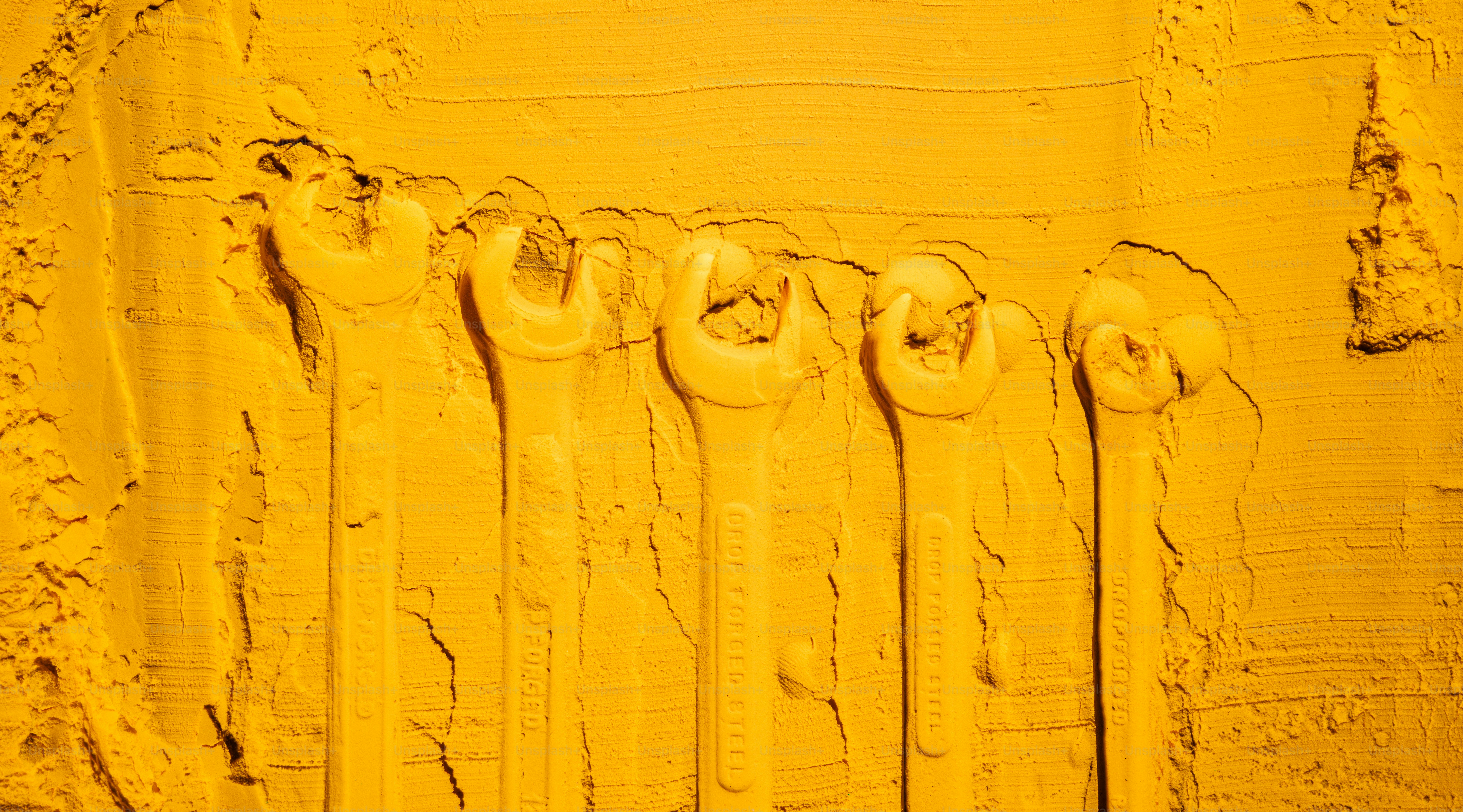 A row of wrenches embedded in yellow powder.