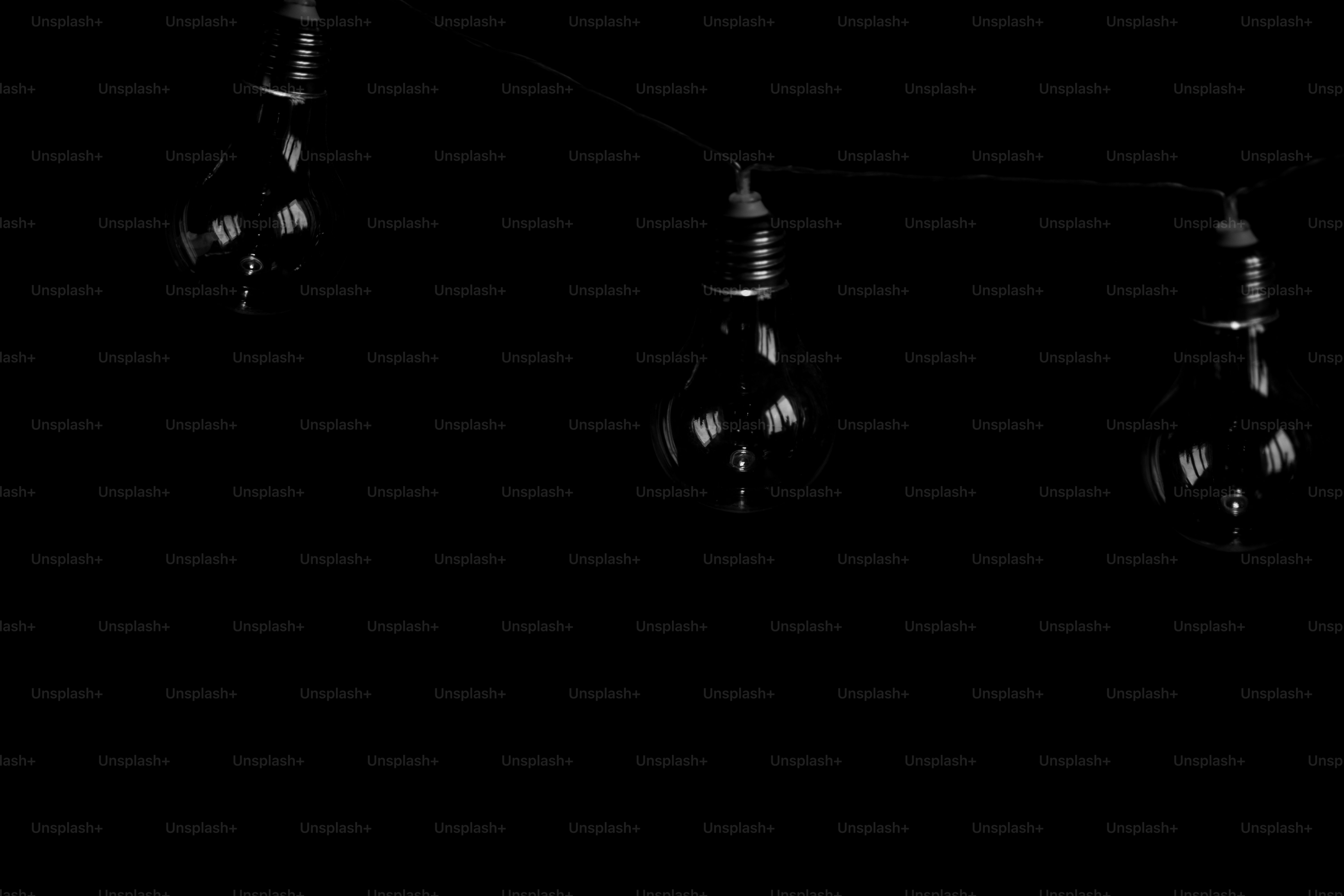 Three vintage light bulbs hanging in darkness