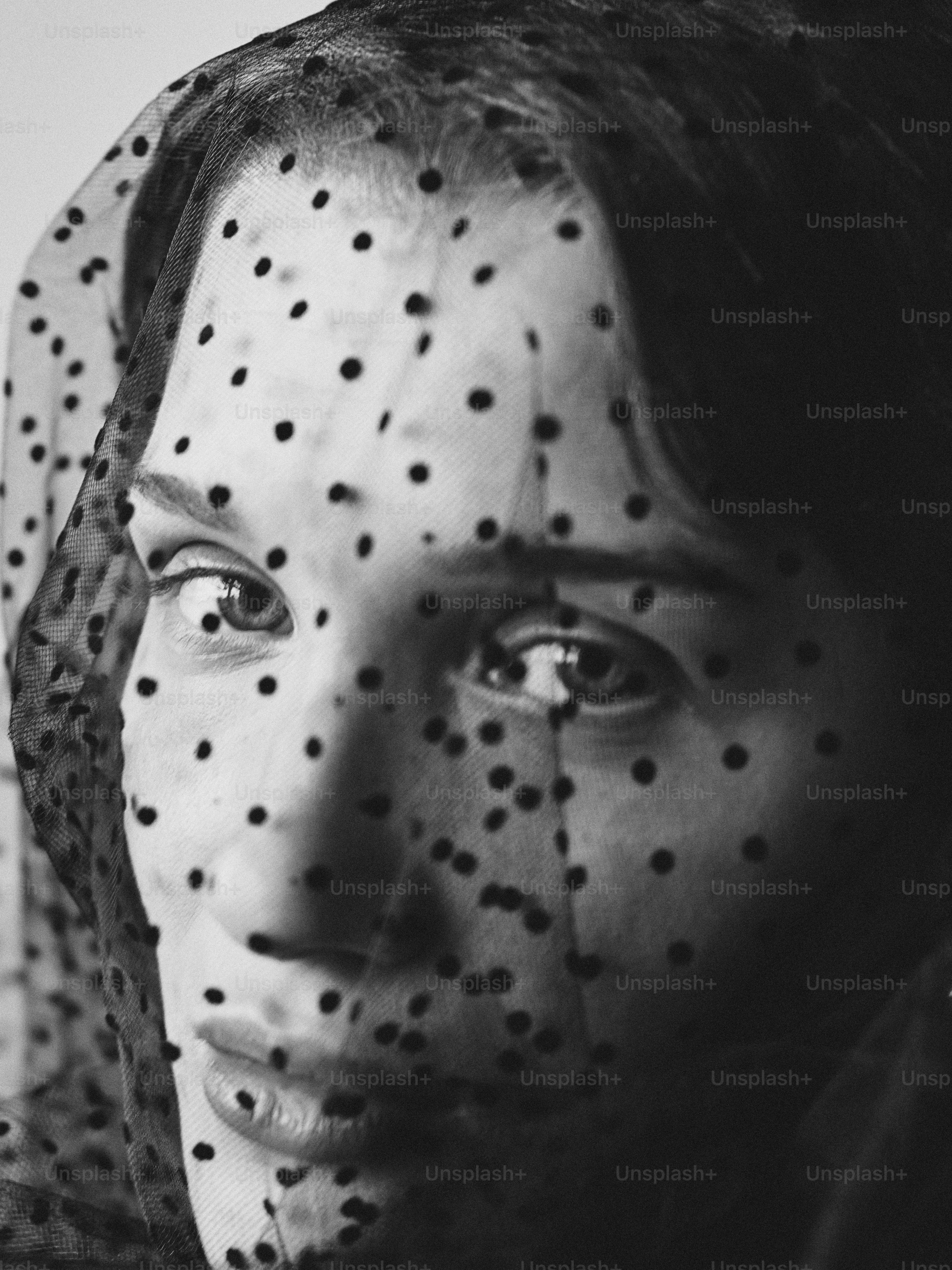 Woman's face obscured by polka dot sheer fabric
