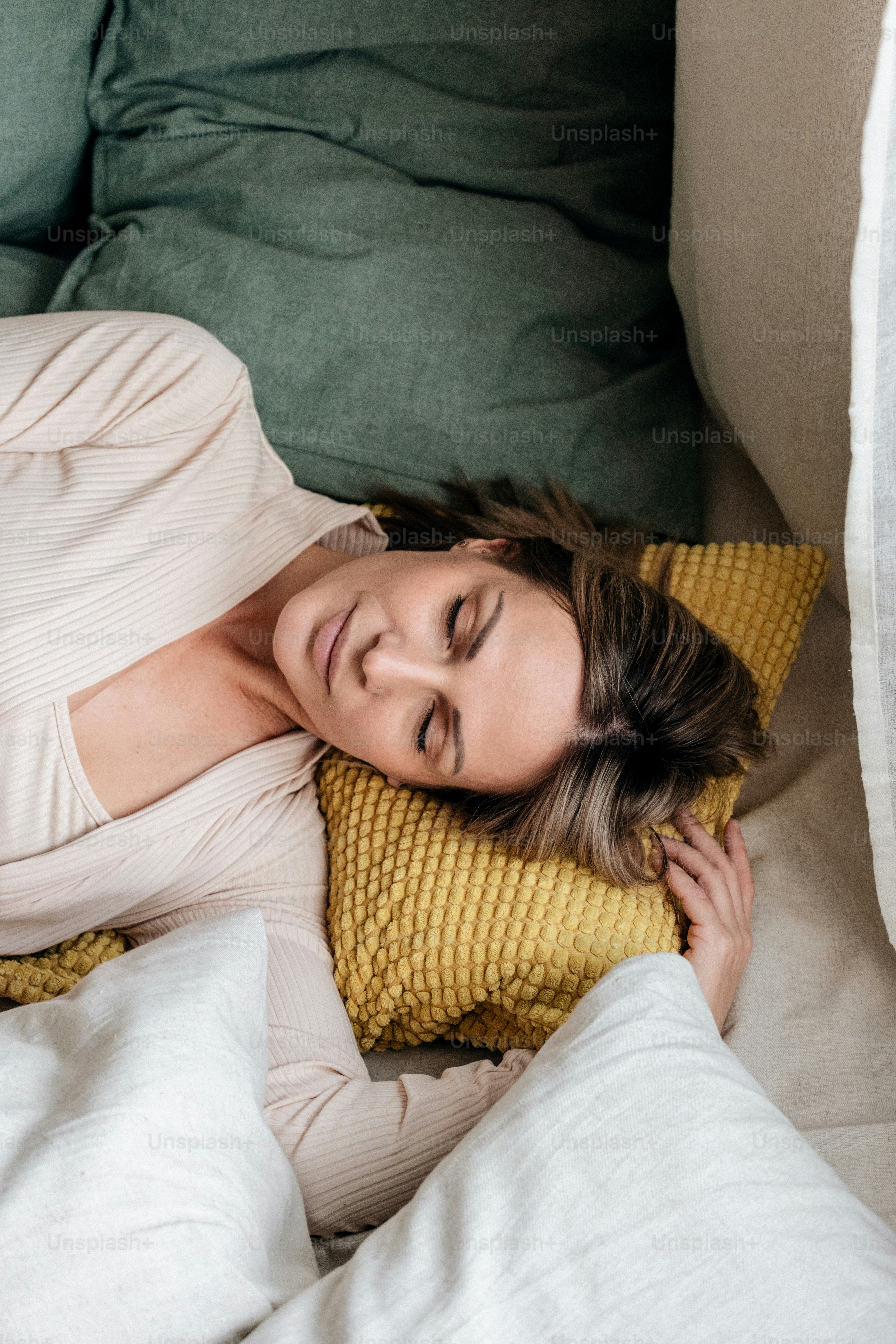 Woman sleeping peacefully on a yellow pillow.