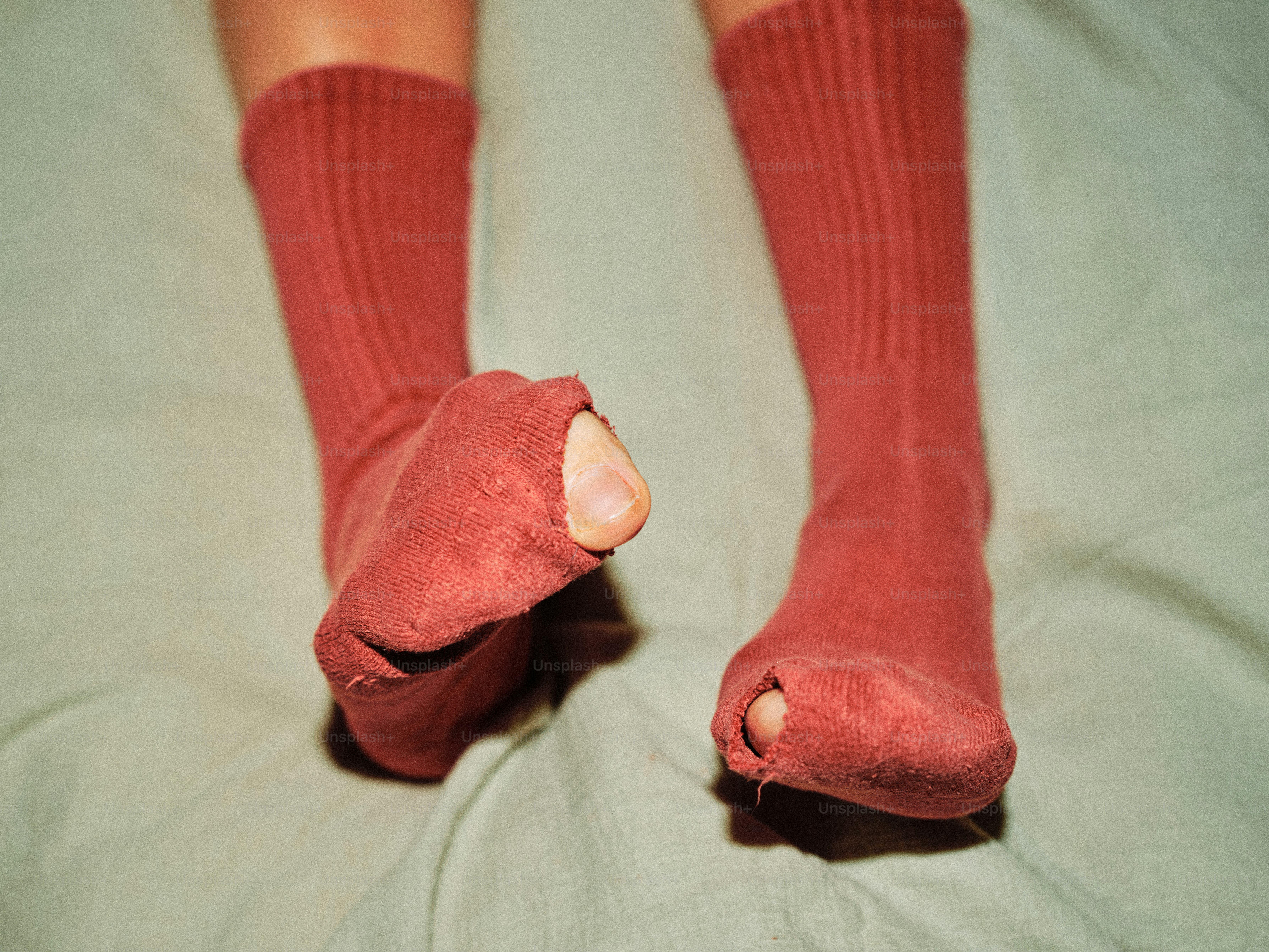Pés com meias gastas em uma cama