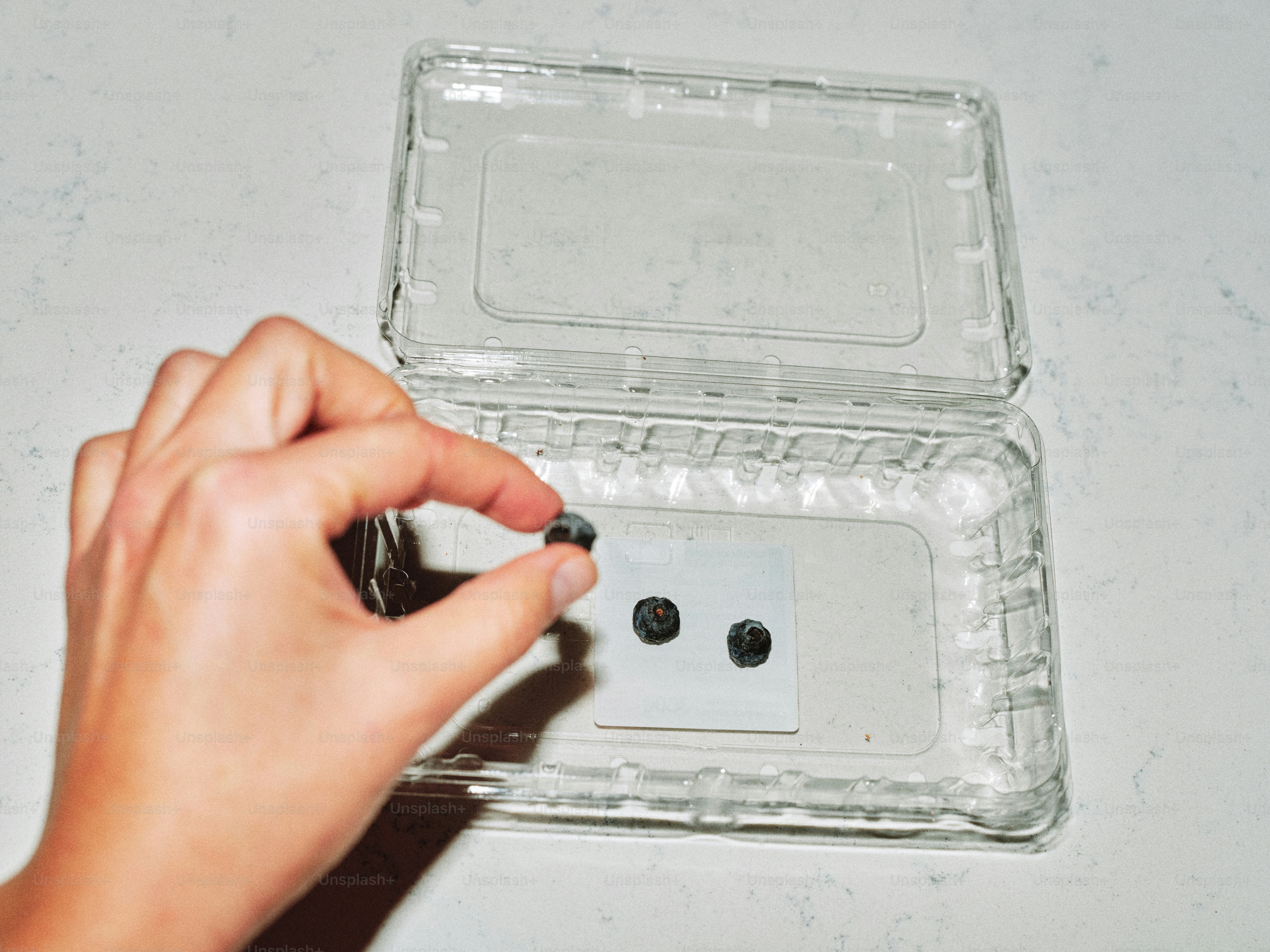 Colocar a mano objetos pequeños en un recipiente de plástico transparente.