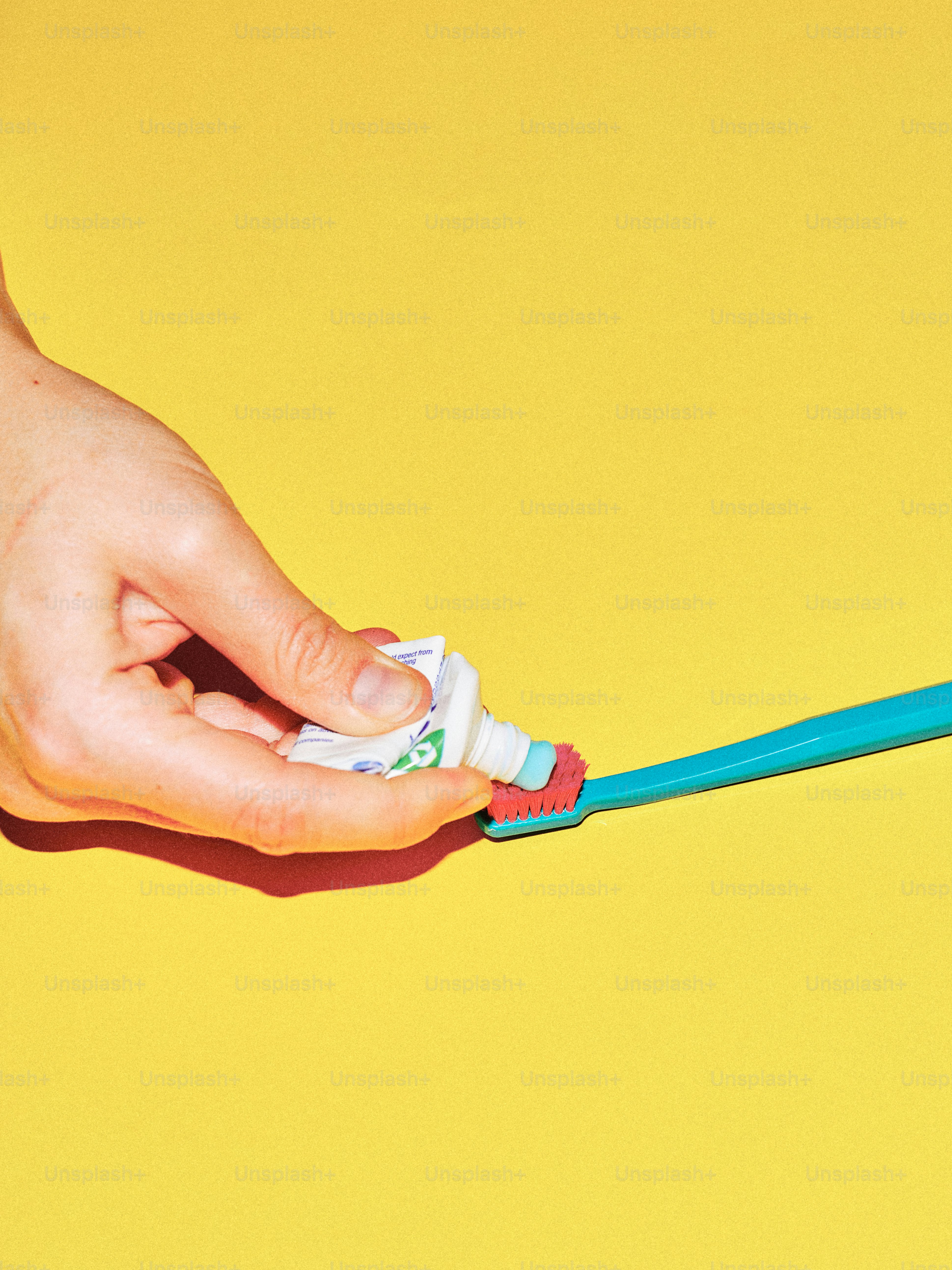Hand squeezing toothpaste onto a toothbrush
