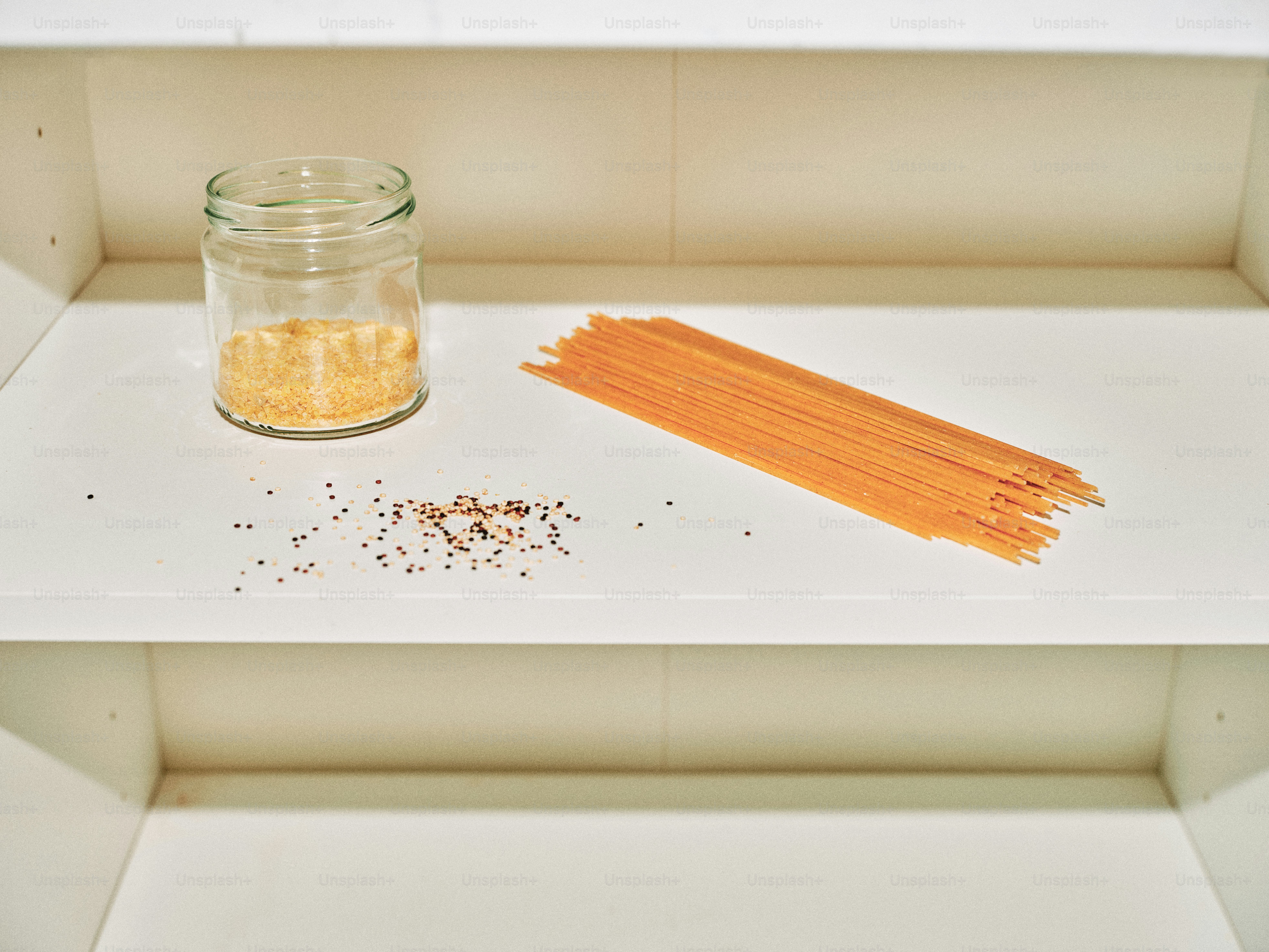 Spaghetti and a jar of spices on a shelf.