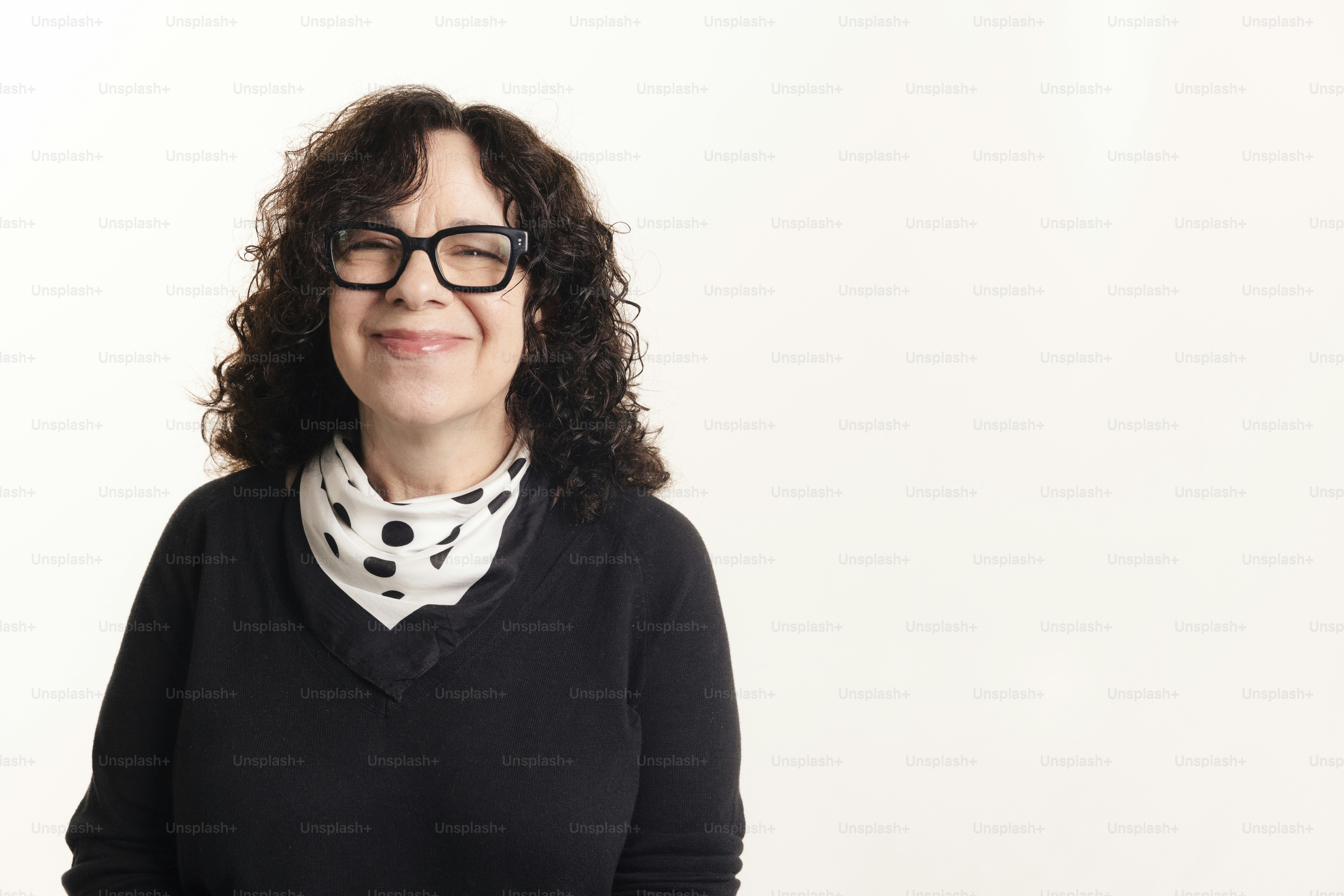 Uma mulher de cabelo cacheado e óculos sorri.