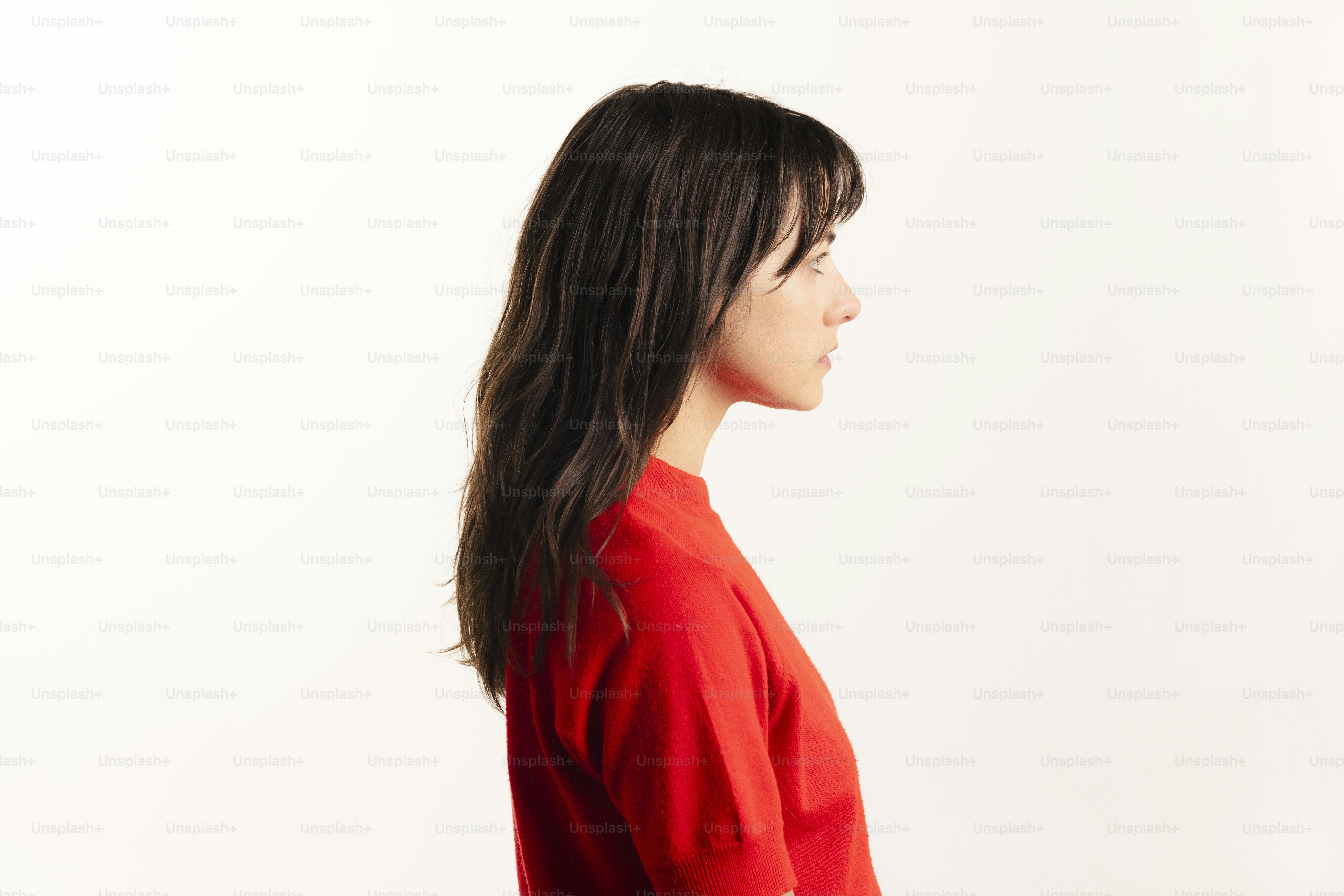 Woman in red shirt facing left on white background