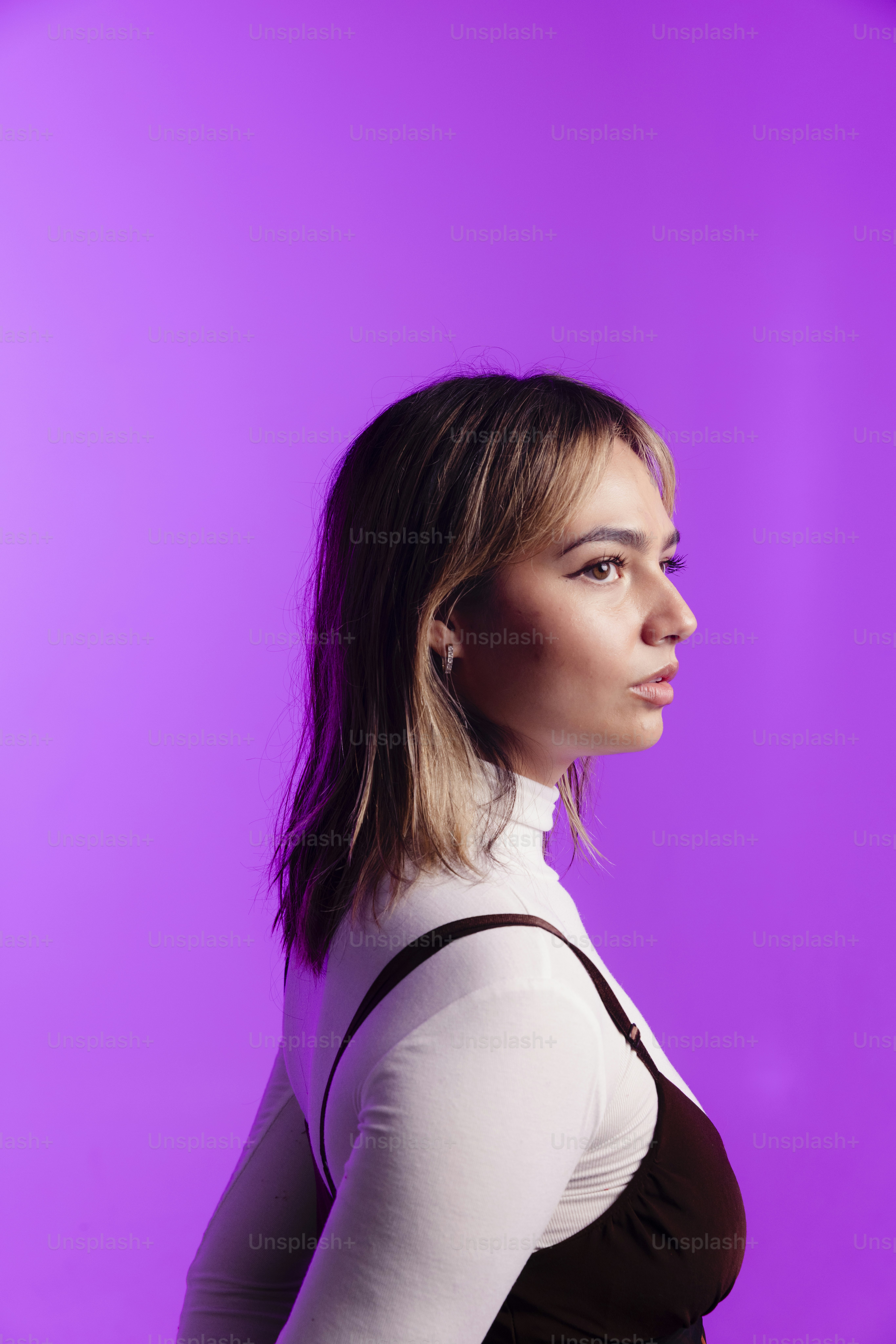 Uma jovem de perfil contra um fundo roxo