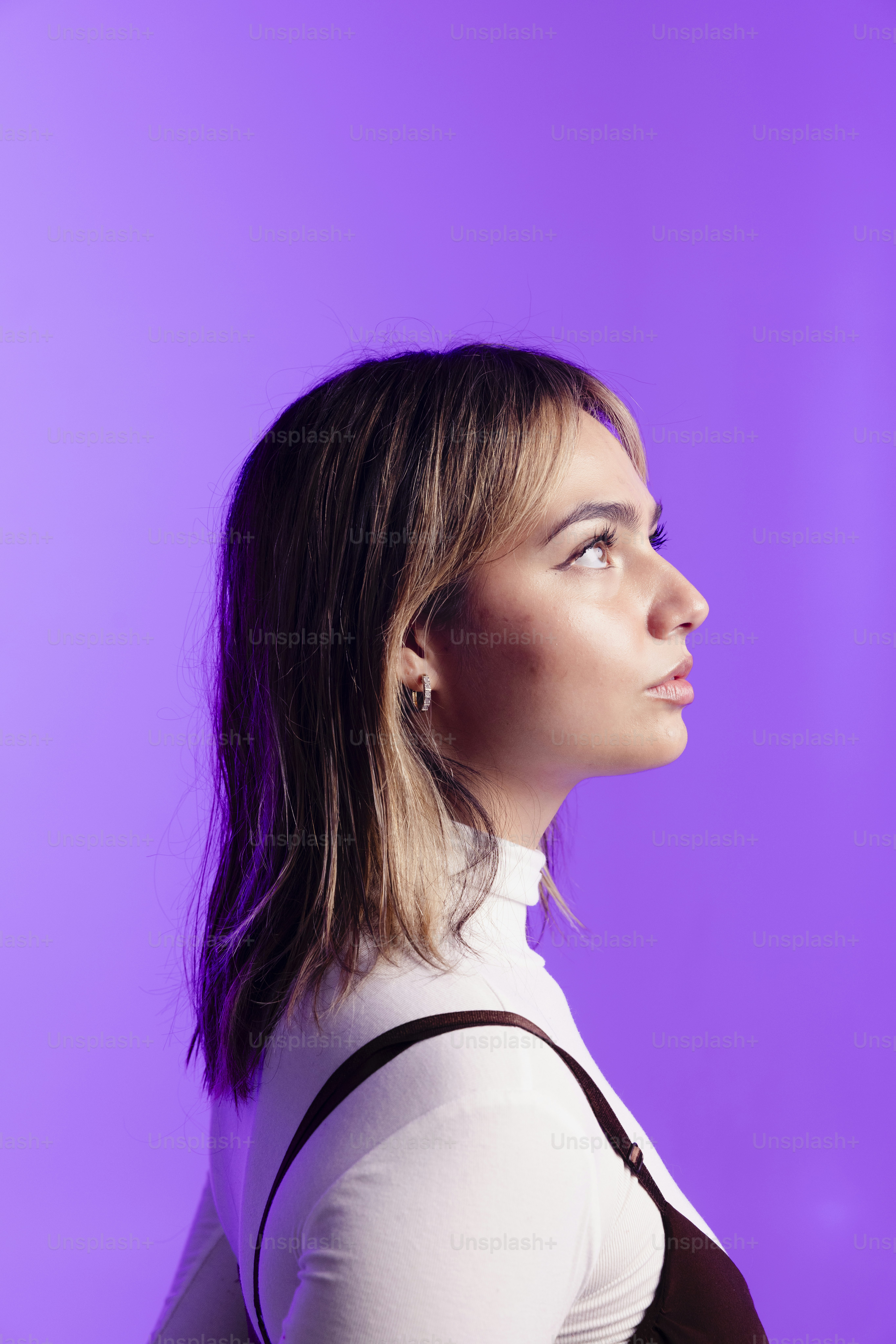 Joven de perfil sobre fondo morado.