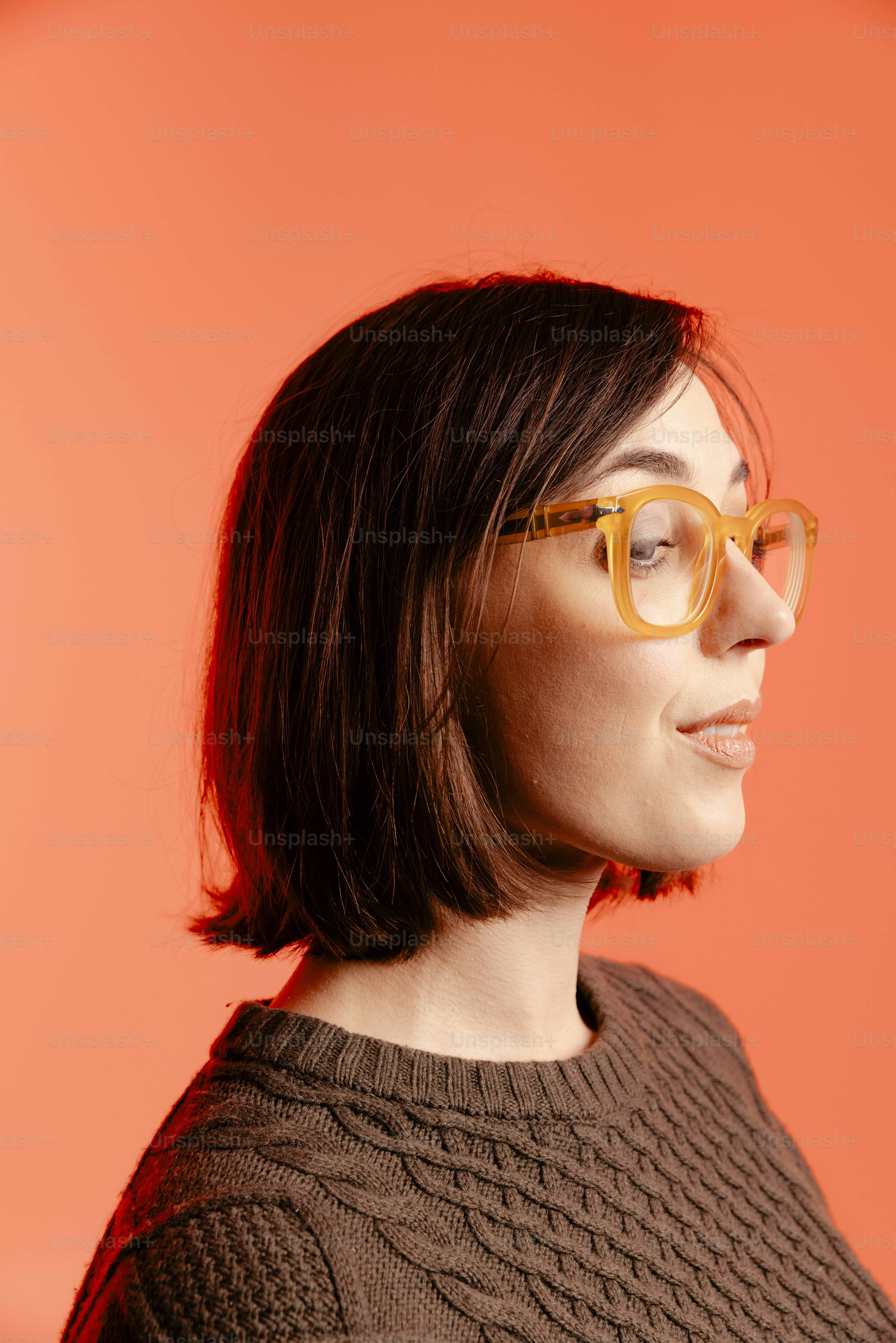 Mulher de óculos contra fundo laranja