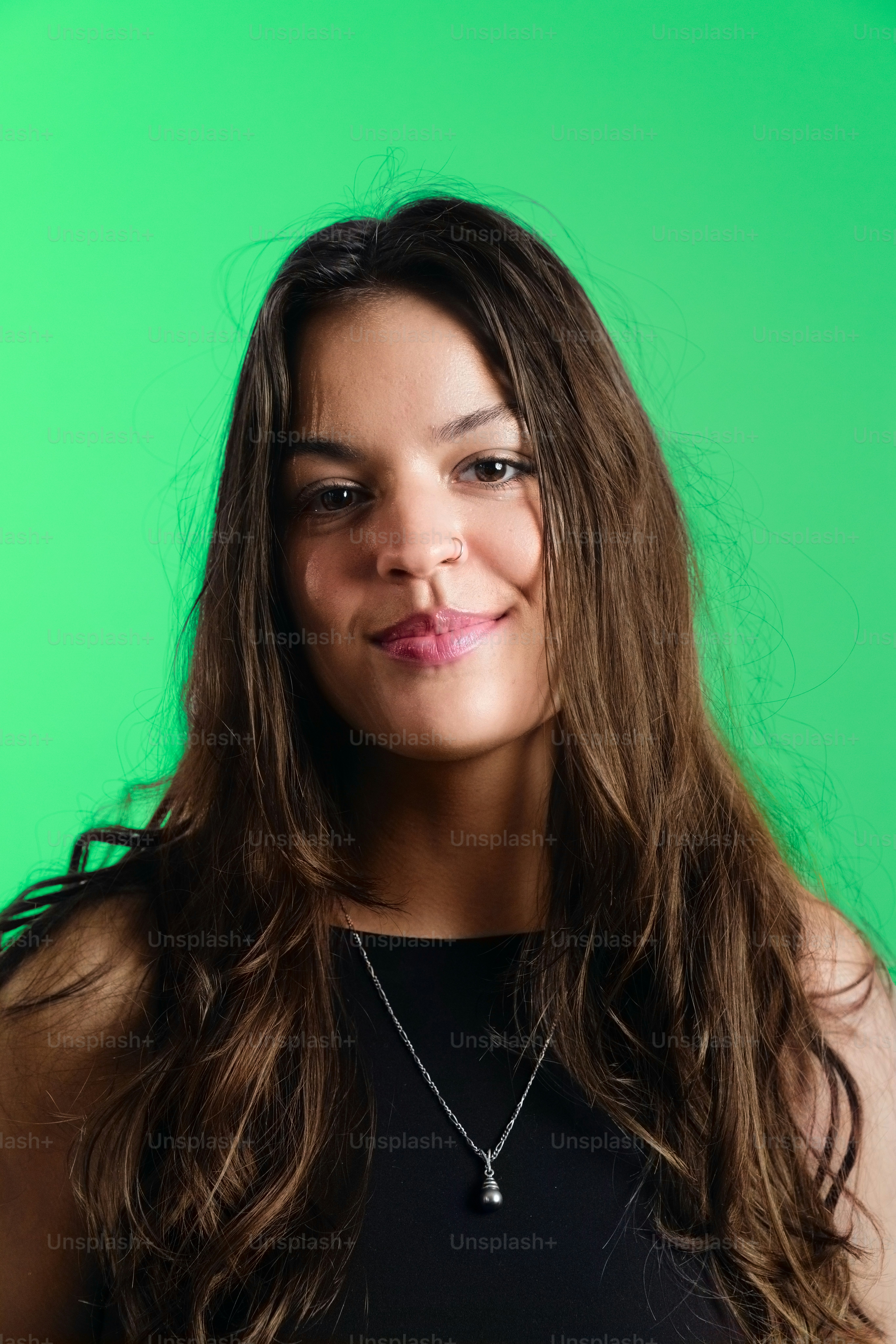 Jovem mulher com longos cabelos castanhos sobre fundo verde