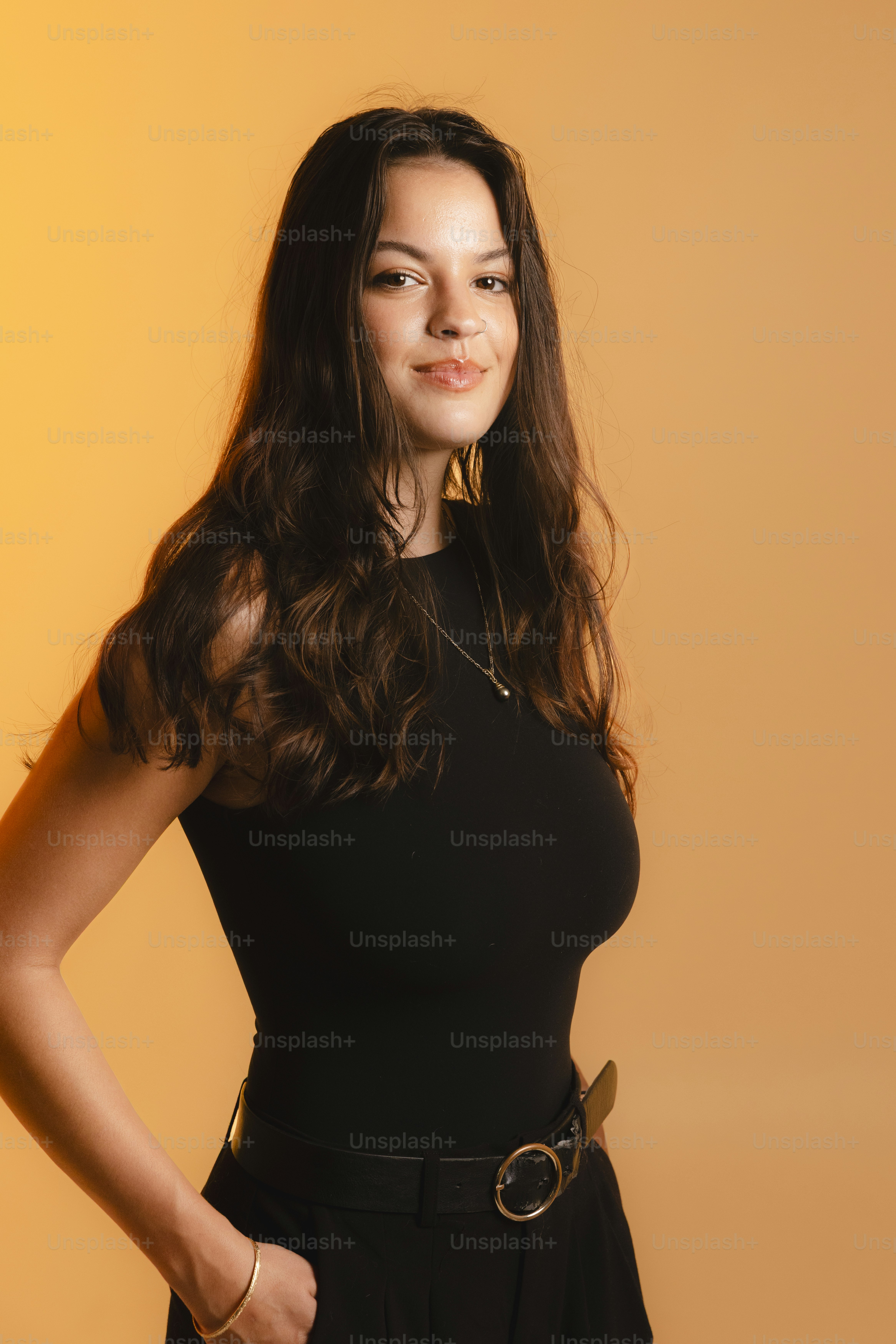 Young woman in black top and pants against orange background