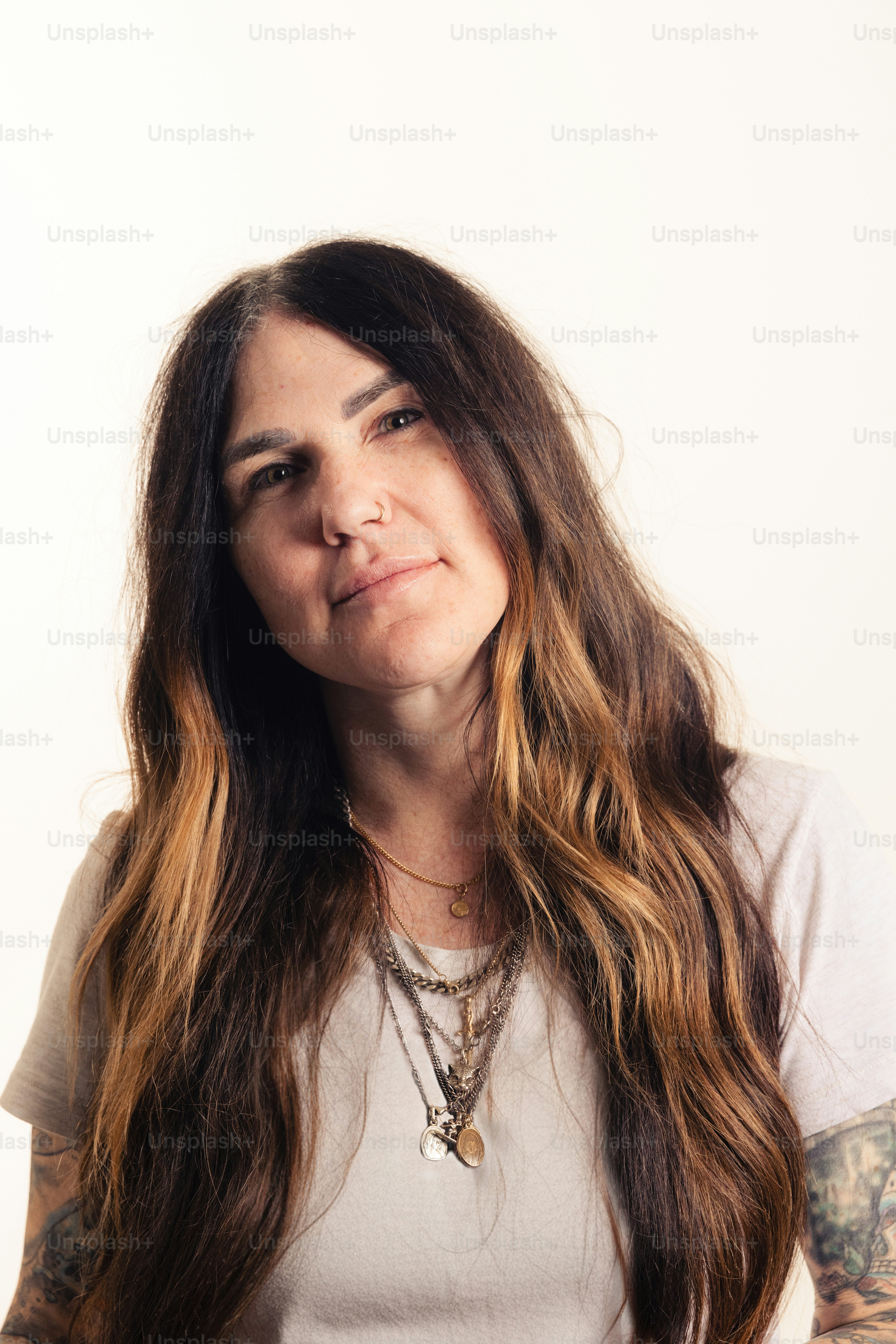 Woman with long, wavy hair and layered necklaces.