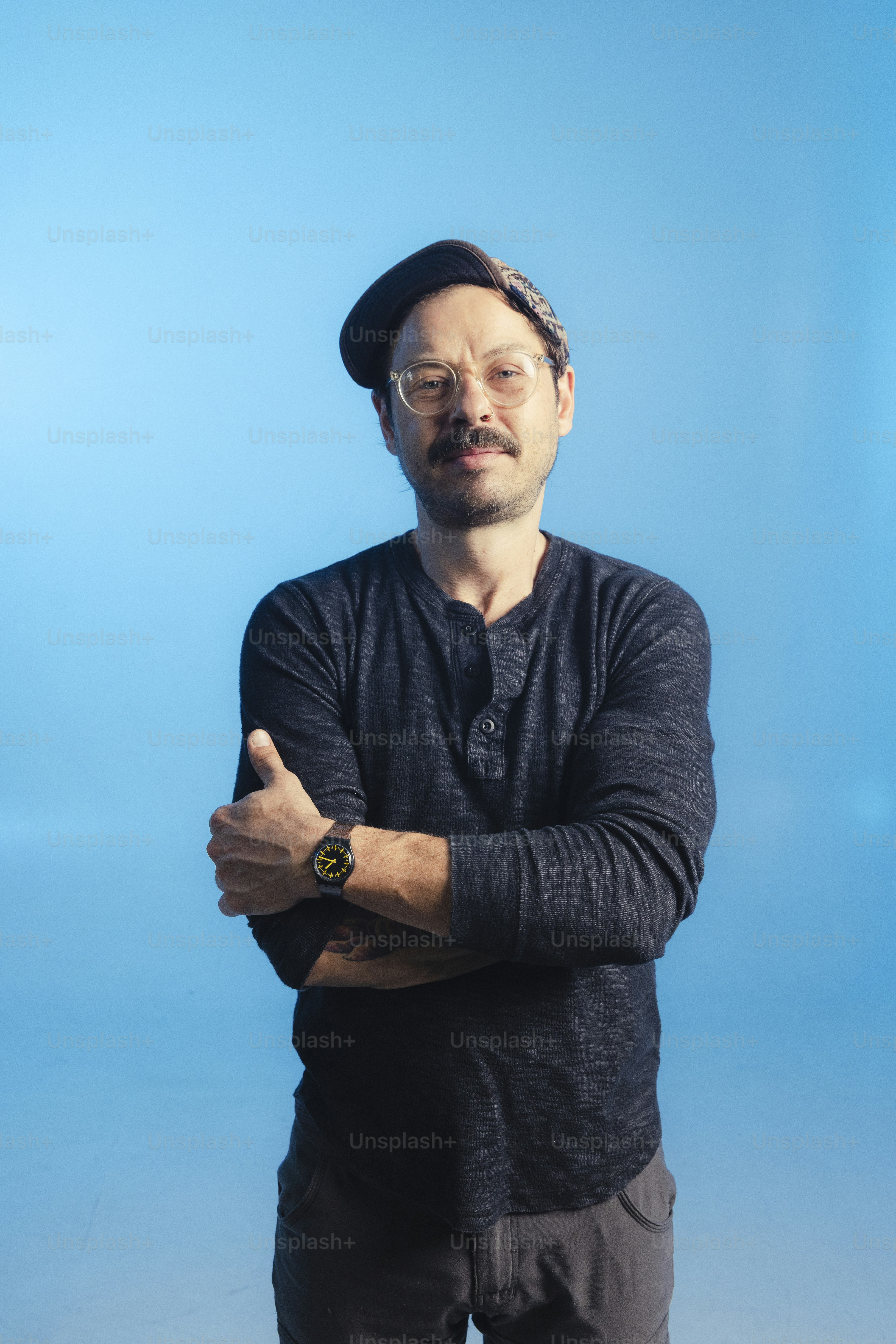 Man wearing a hat and glasses with arms crossed.