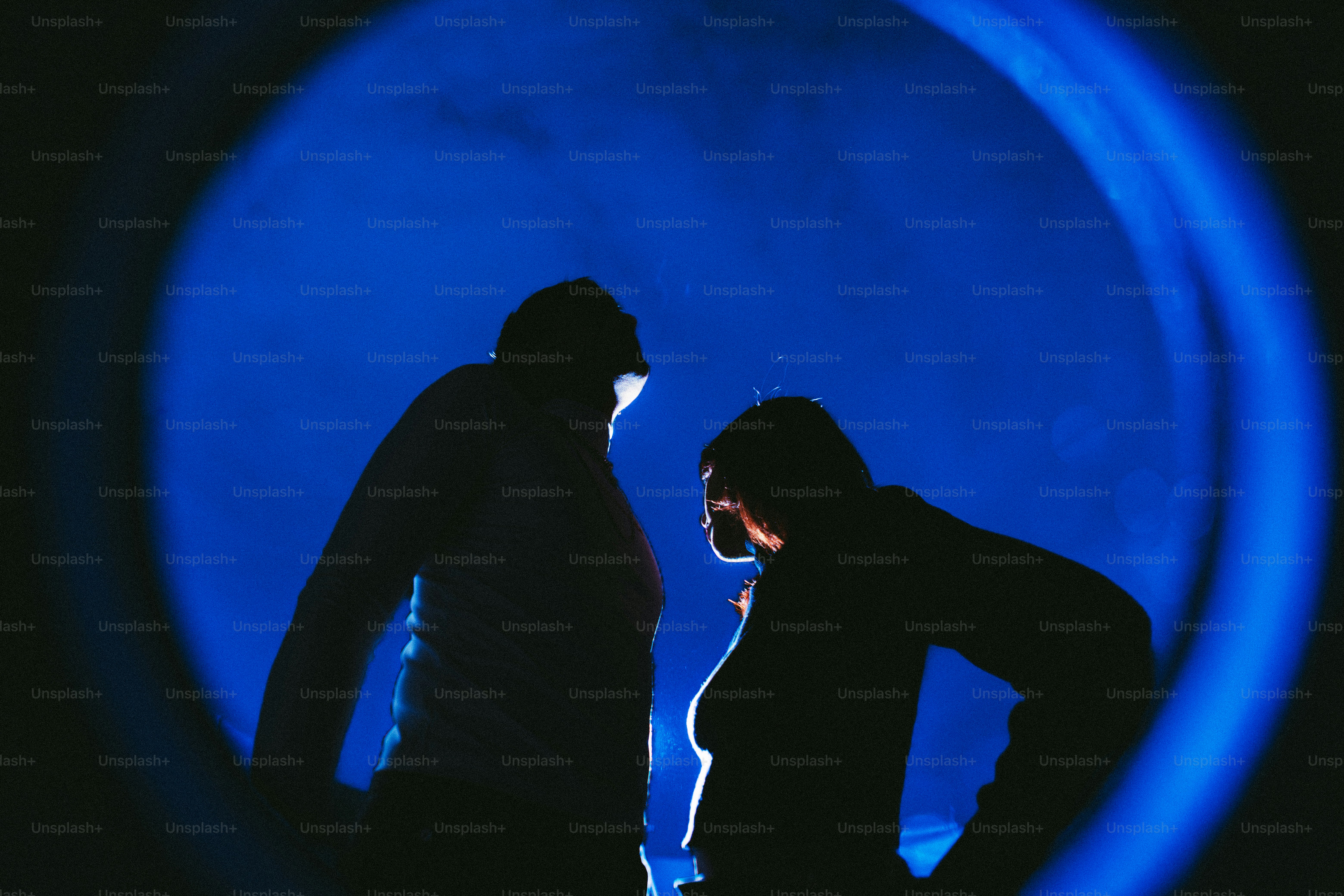 Silhouettes de deux personnes contre une lumière bleue