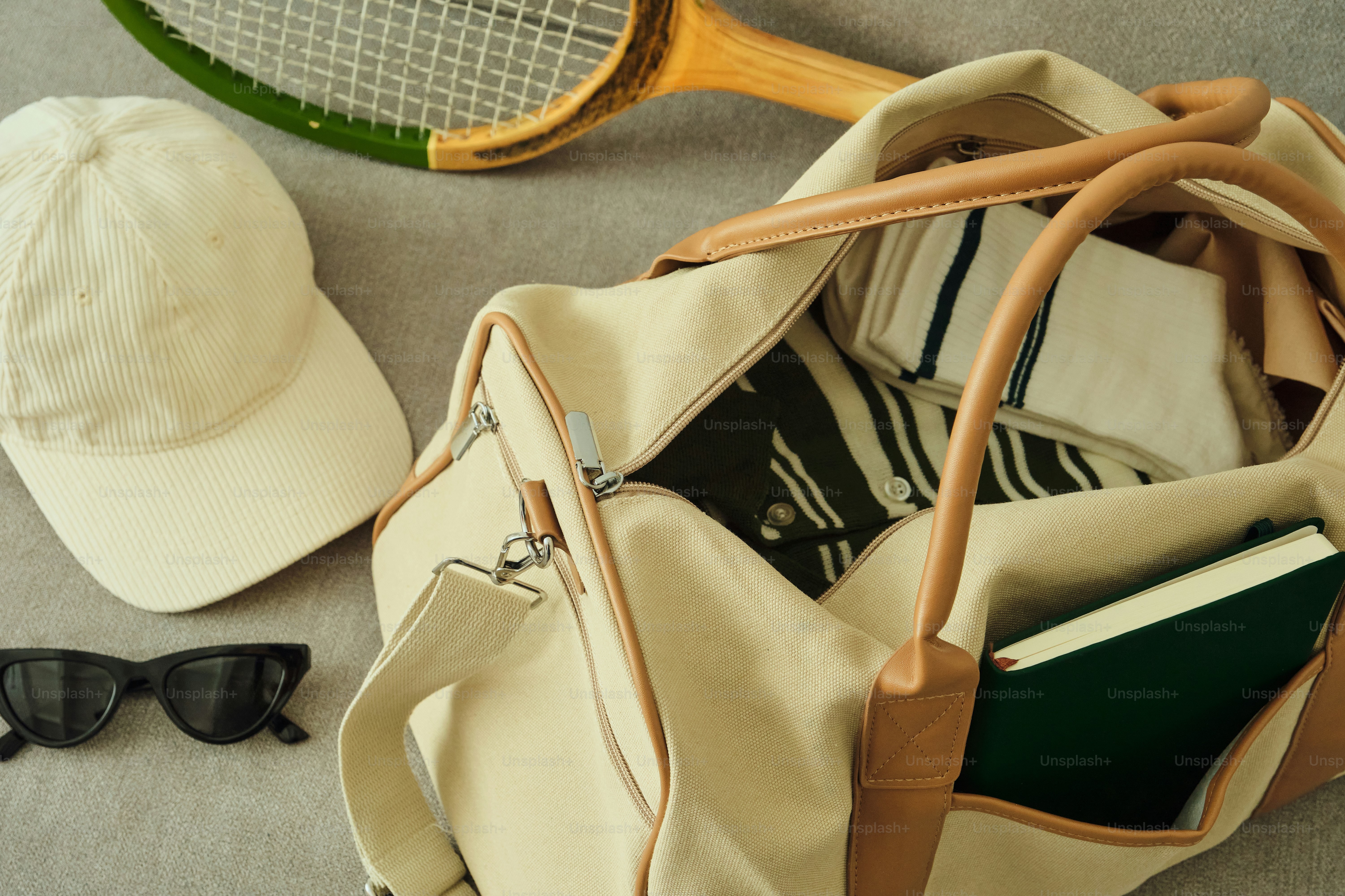Raket tenis, topi, kacamata hitam, dan tas ransel di permukaan