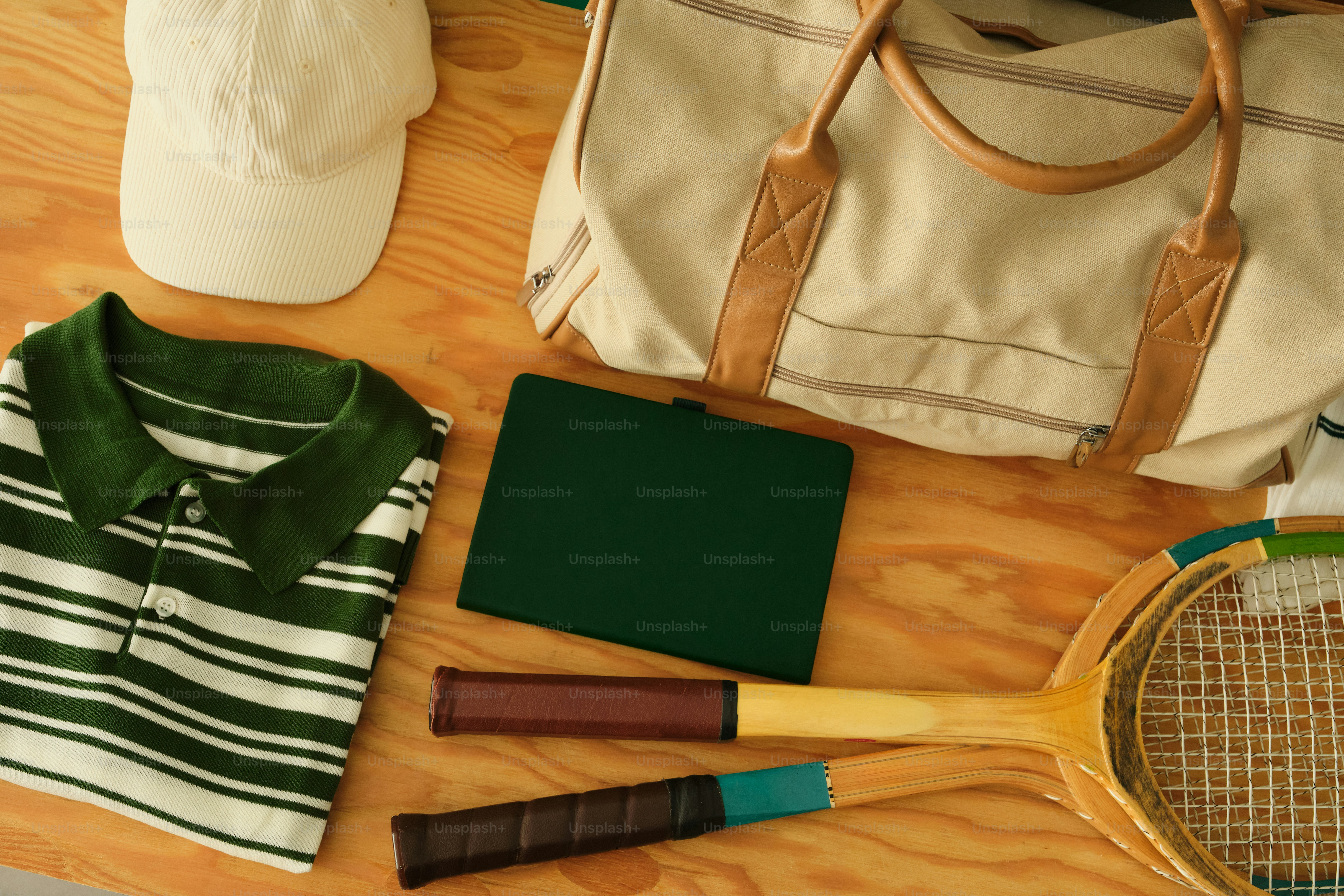 Tennis racket, polo shirt, and duffel bag on wooden surface. photo ...