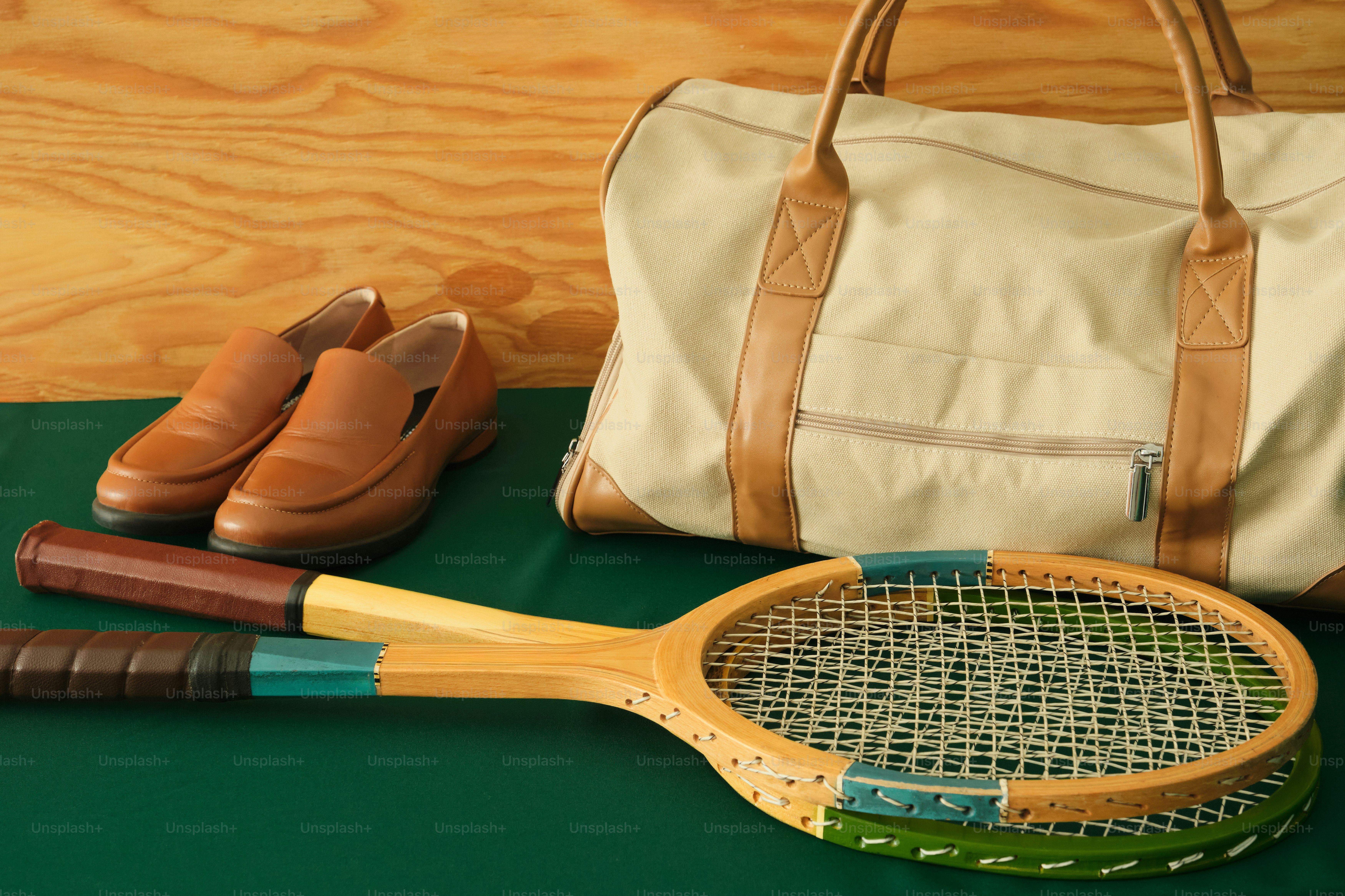Tennis racket, polo shirt, and duffel bag on wooden surface. photo ...