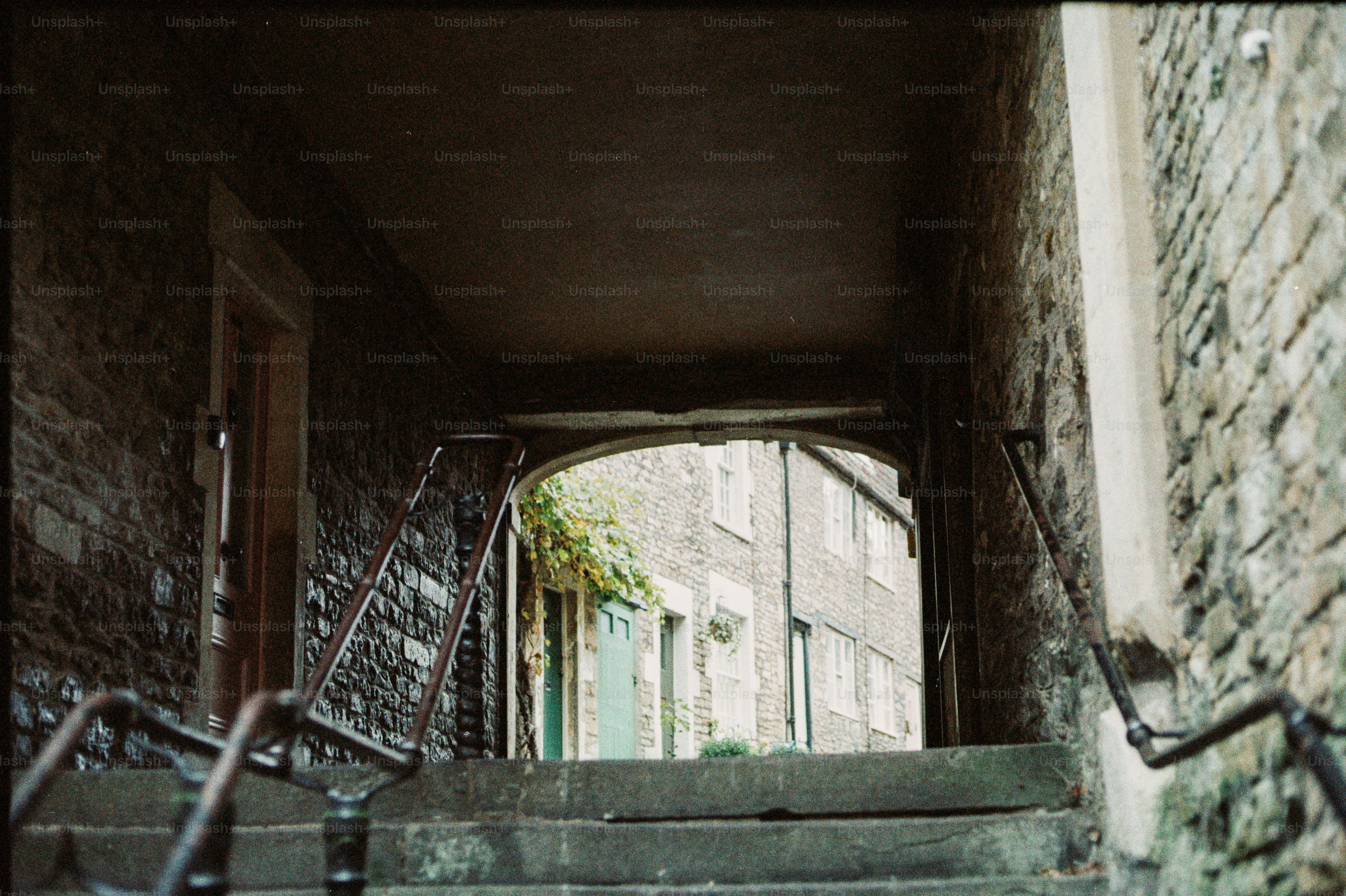 Stone steps leading through a dark archway to buildings.