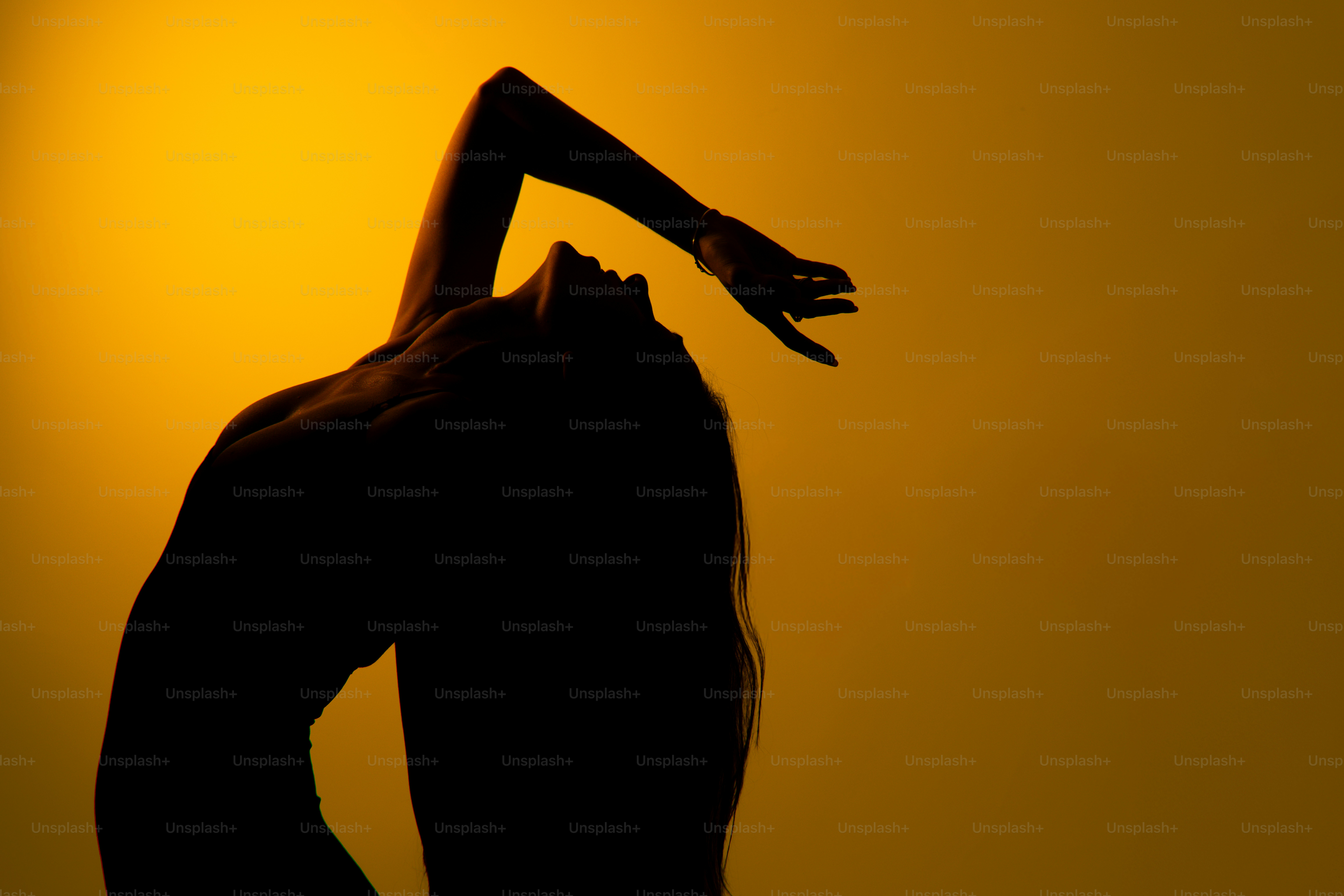 Silhouette einer Frau, die vor gelbem Hintergrund tanzt