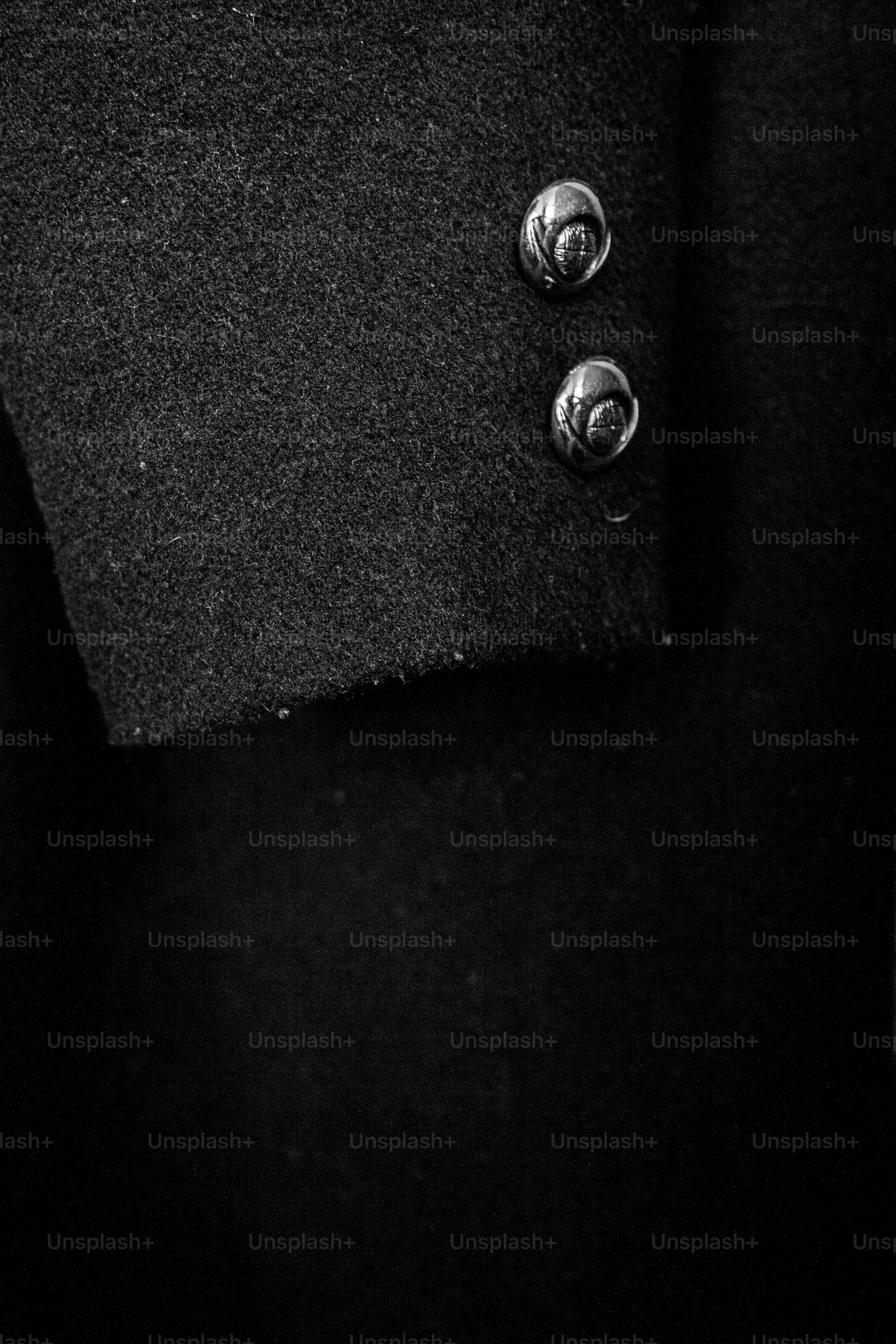 Primer plano de dos botones plateados sobre un abrigo negro