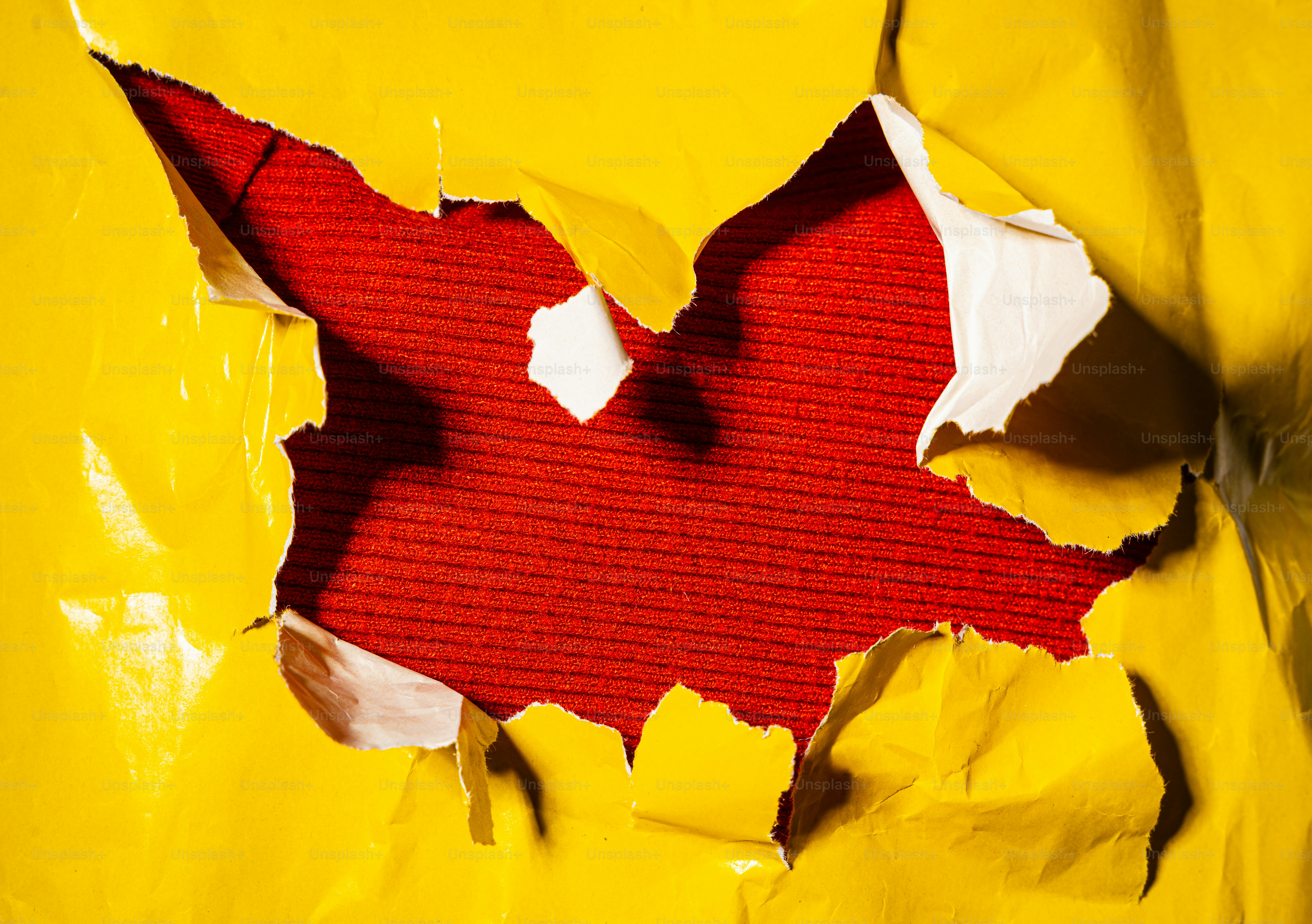 Torn yellow paper revealing textured red background