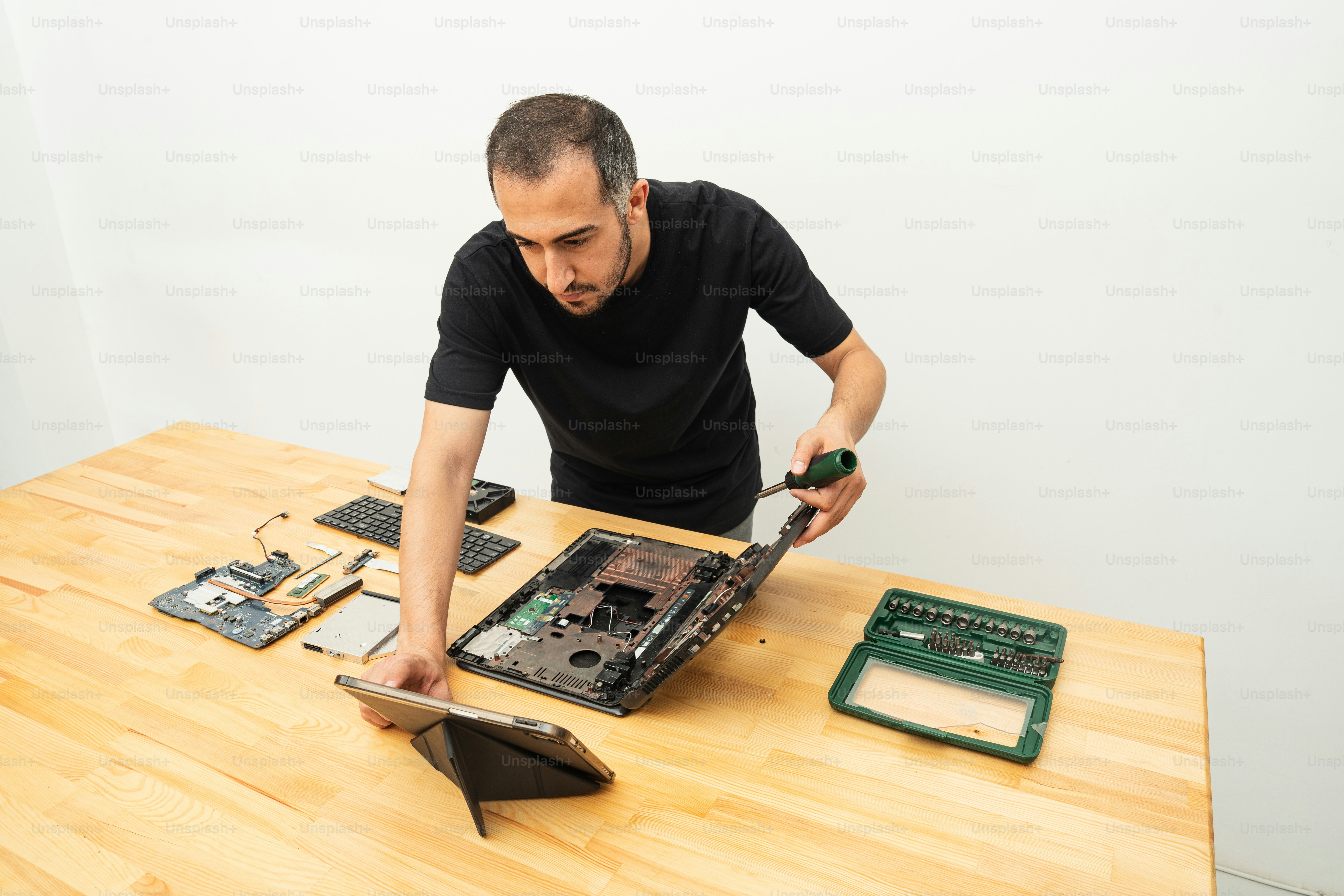 Pria membongkar laptop di atas meja kayu.