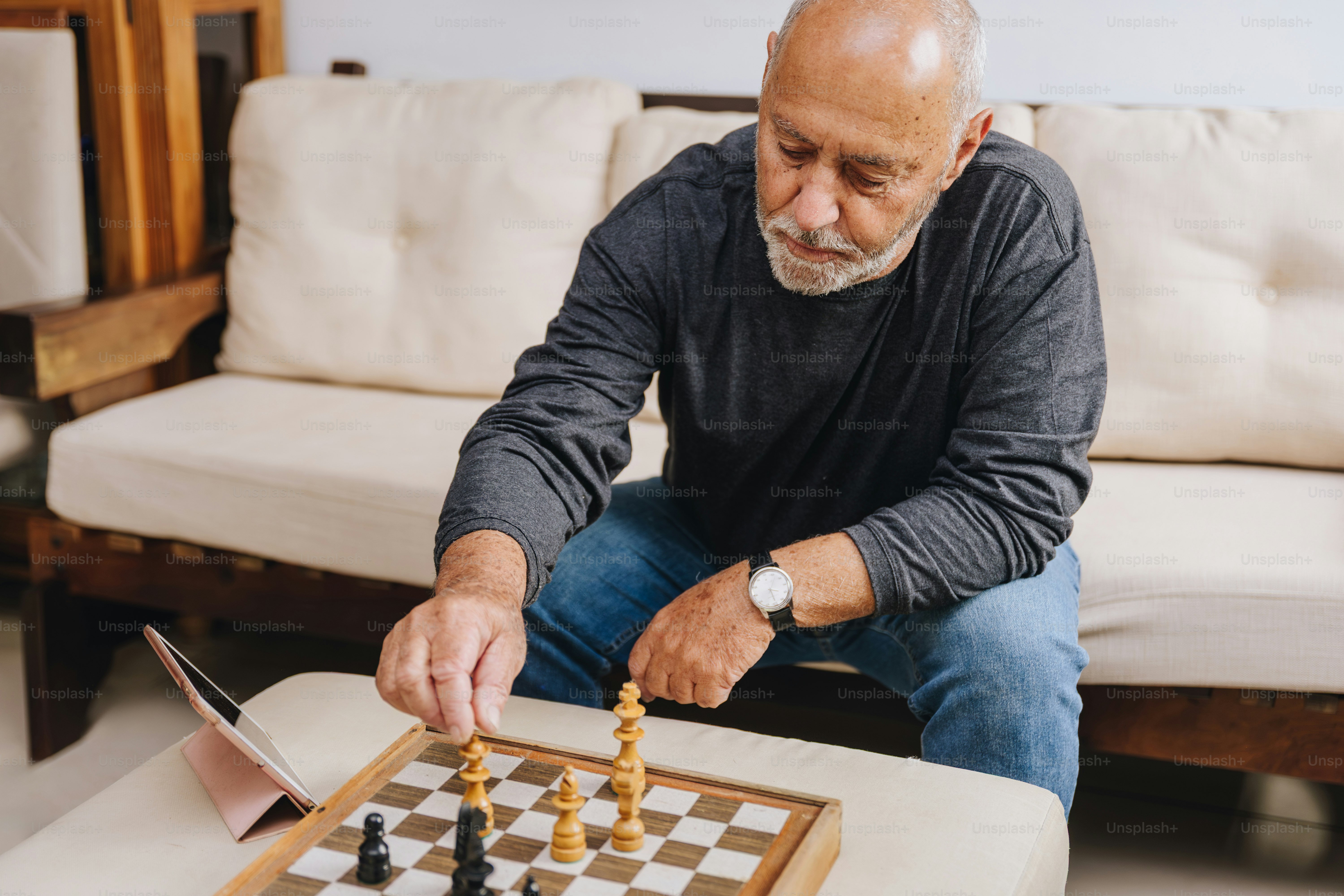 Elderly man playing chess on a wooden board