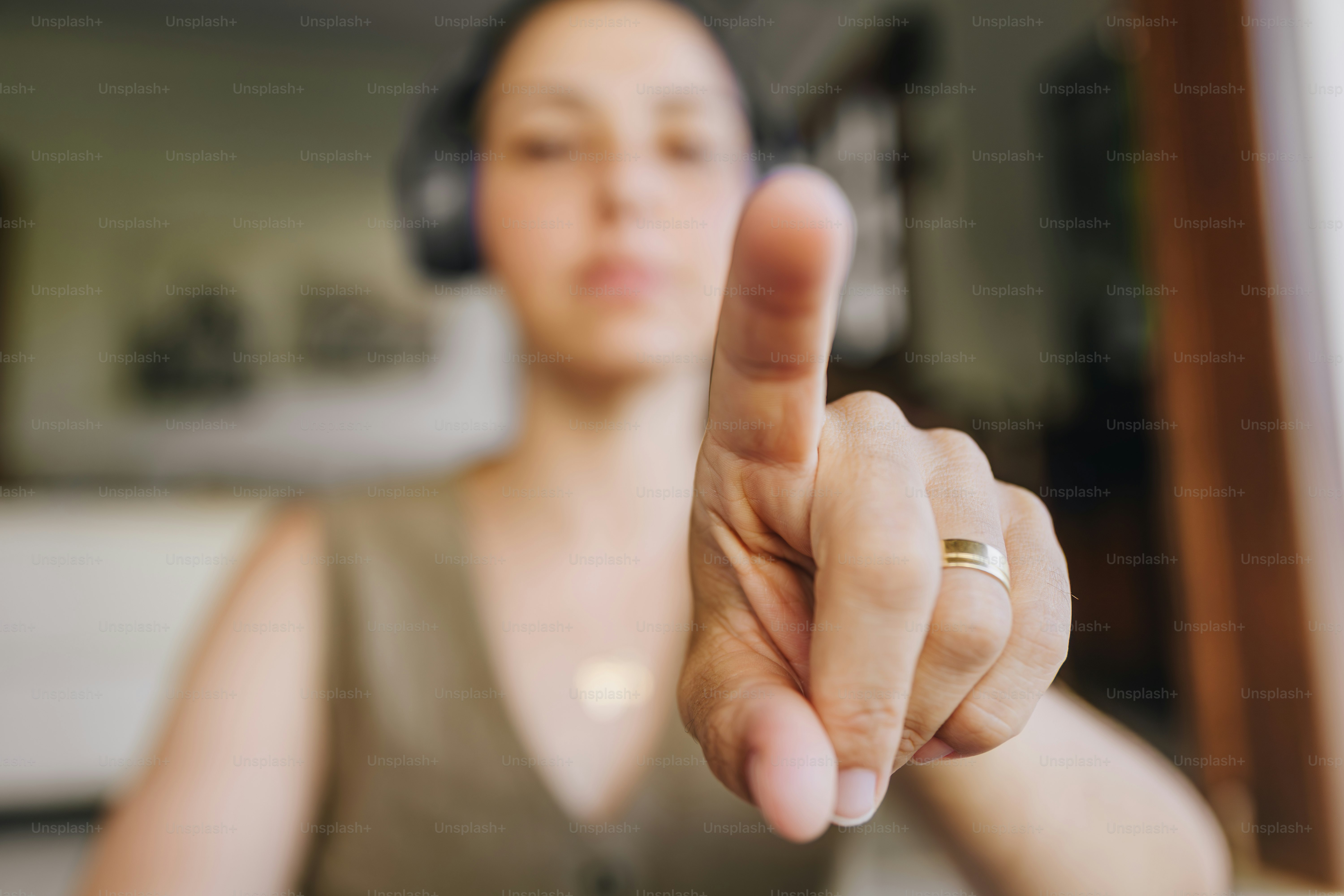 Woman in headphones points finger towards camera