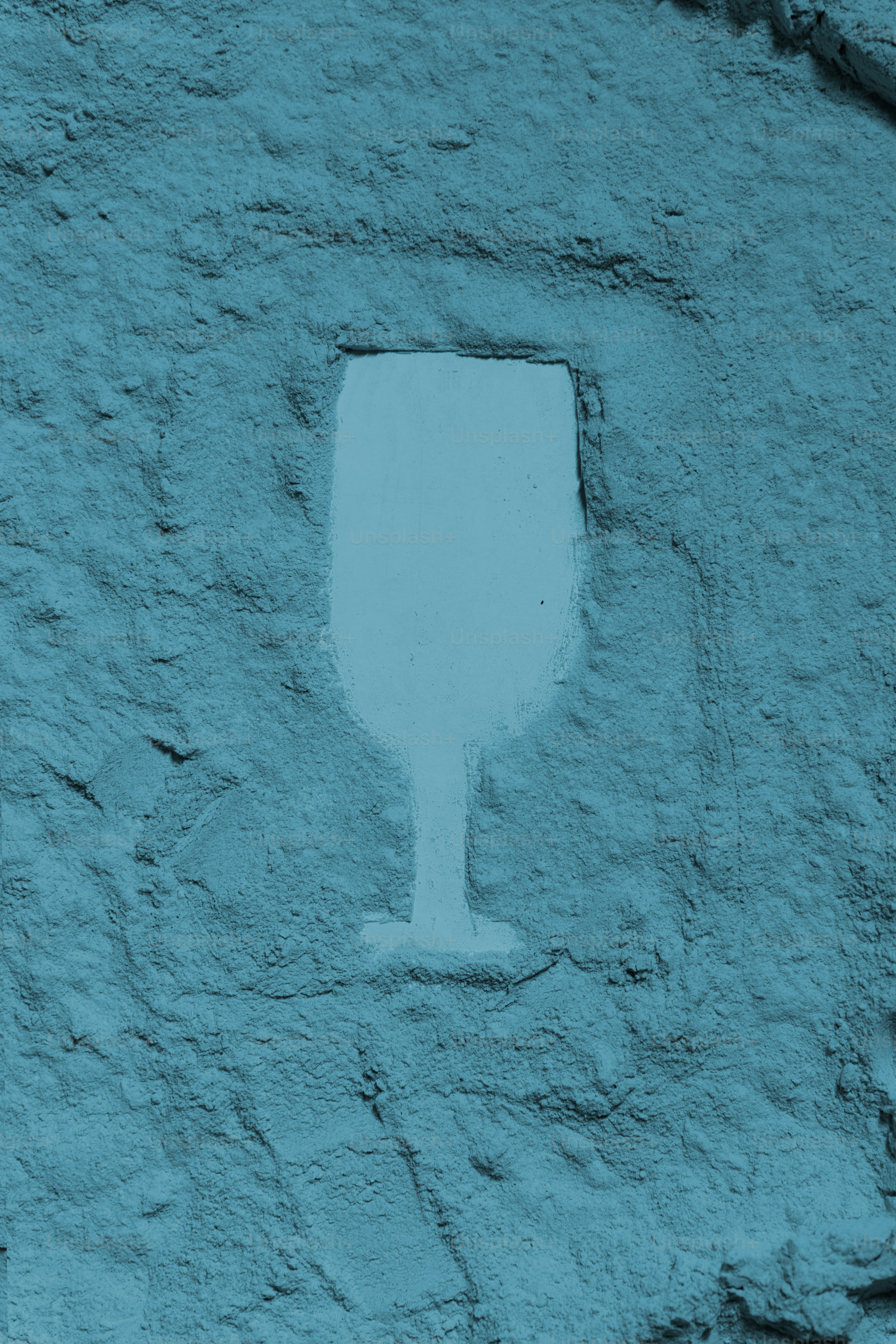 A silhouette of a wine glass on a textured wall.