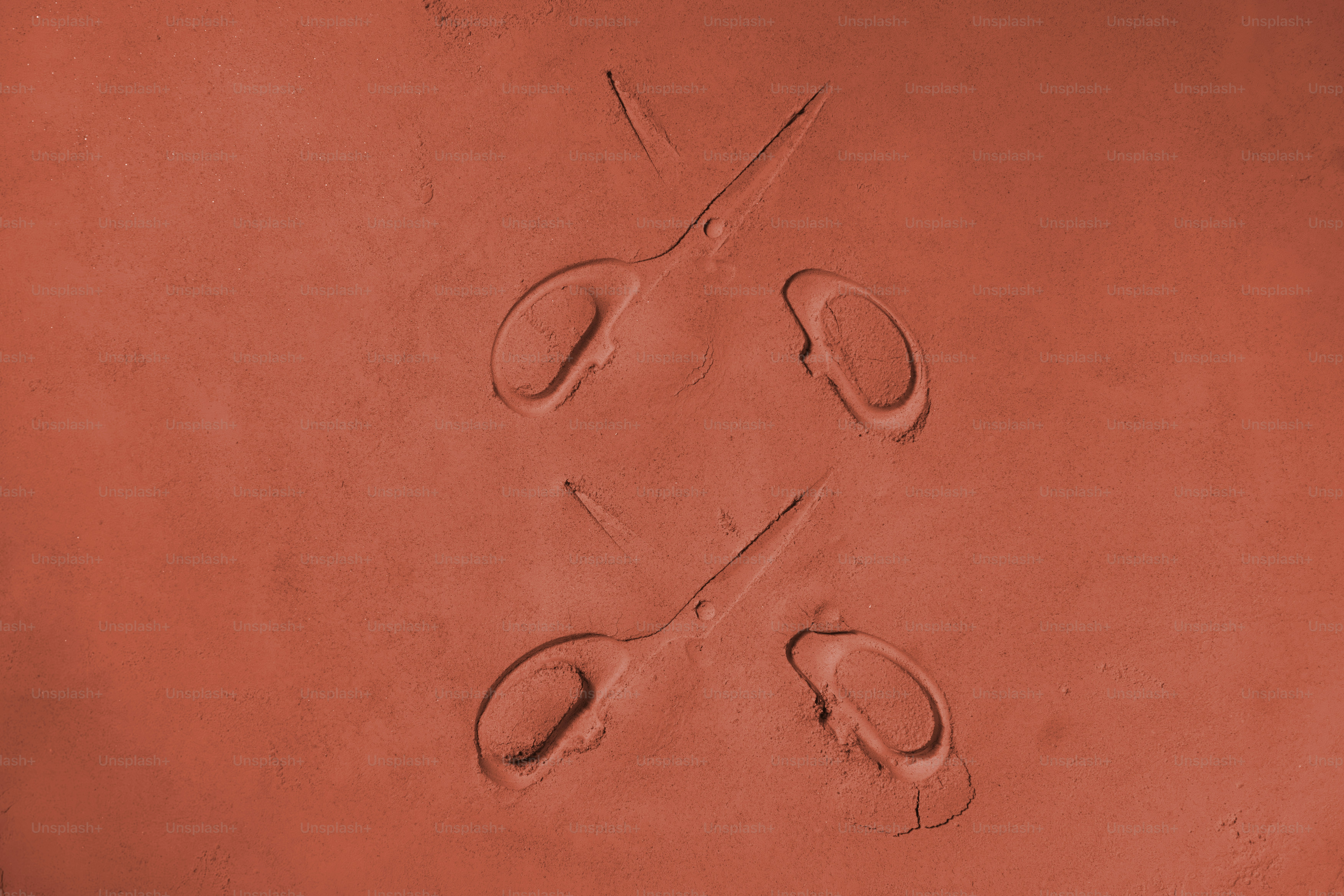 赤い粘土に刻印された2対のハサミ