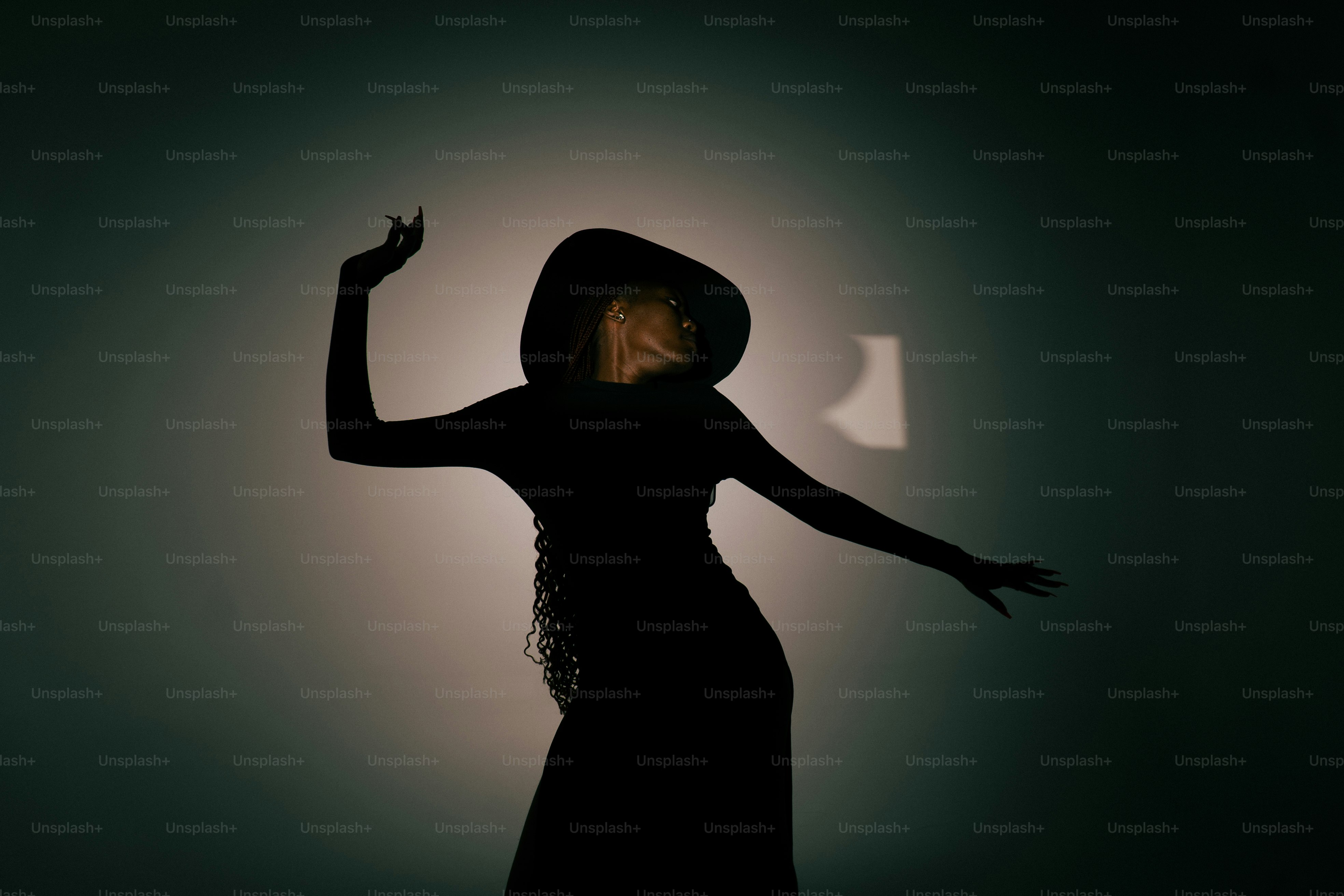 Silueta de una mujer con un sombrero de ala ancha bailando.