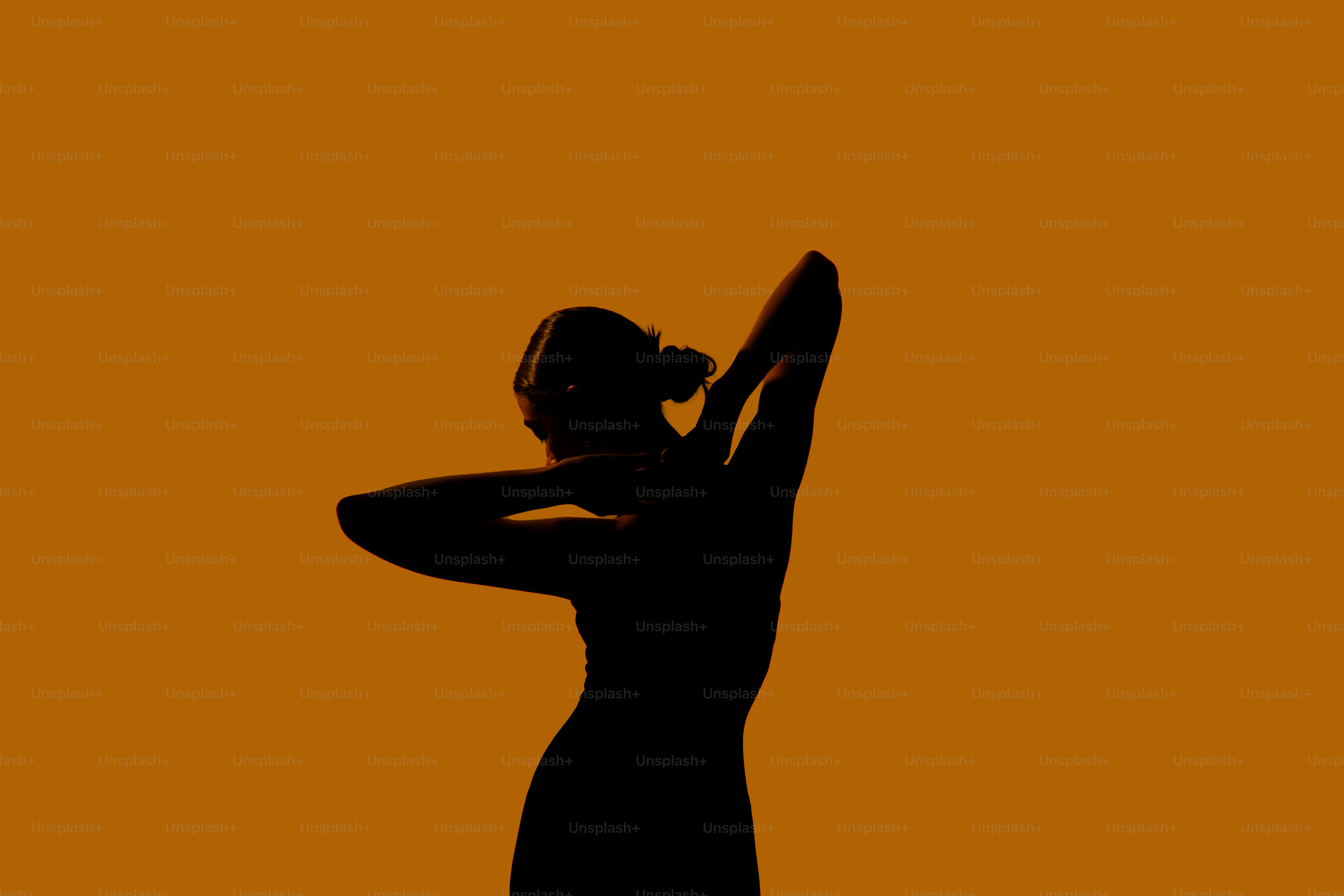 Silueta de una mujer bailando sobre un fondo naranja