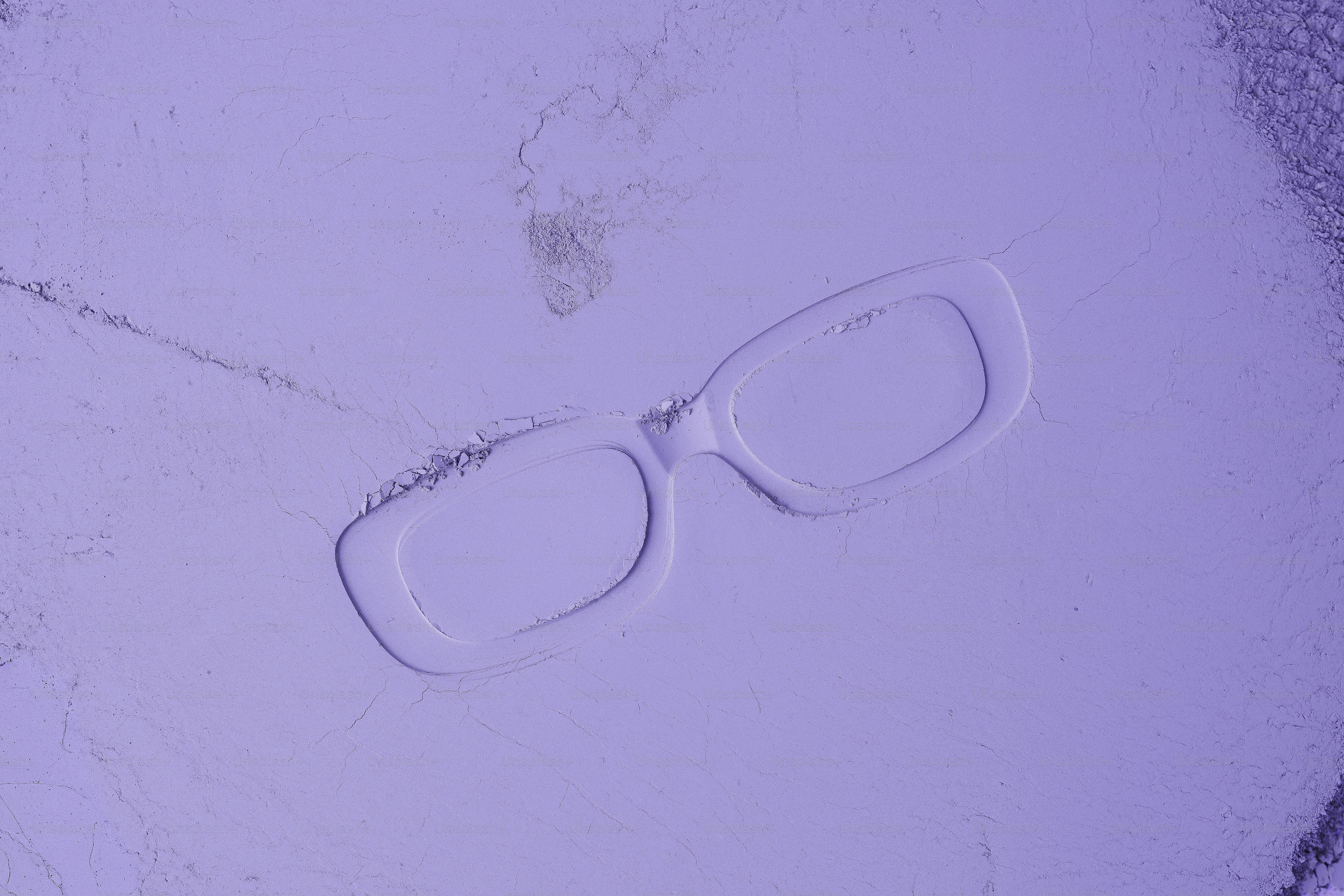 Empreintes de lunettes blanches sur une surface violet clair