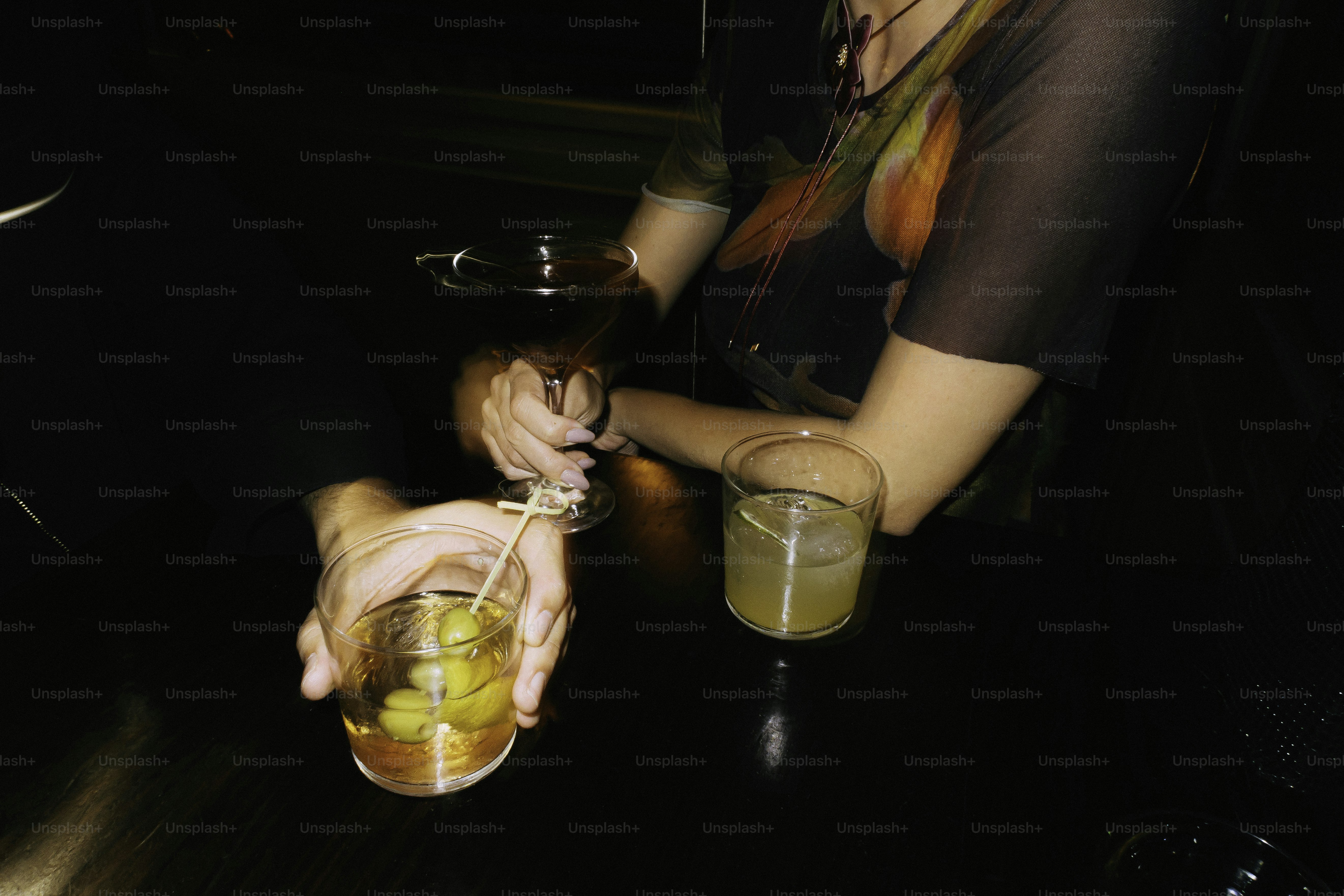 Hands holding cocktails with olives at night