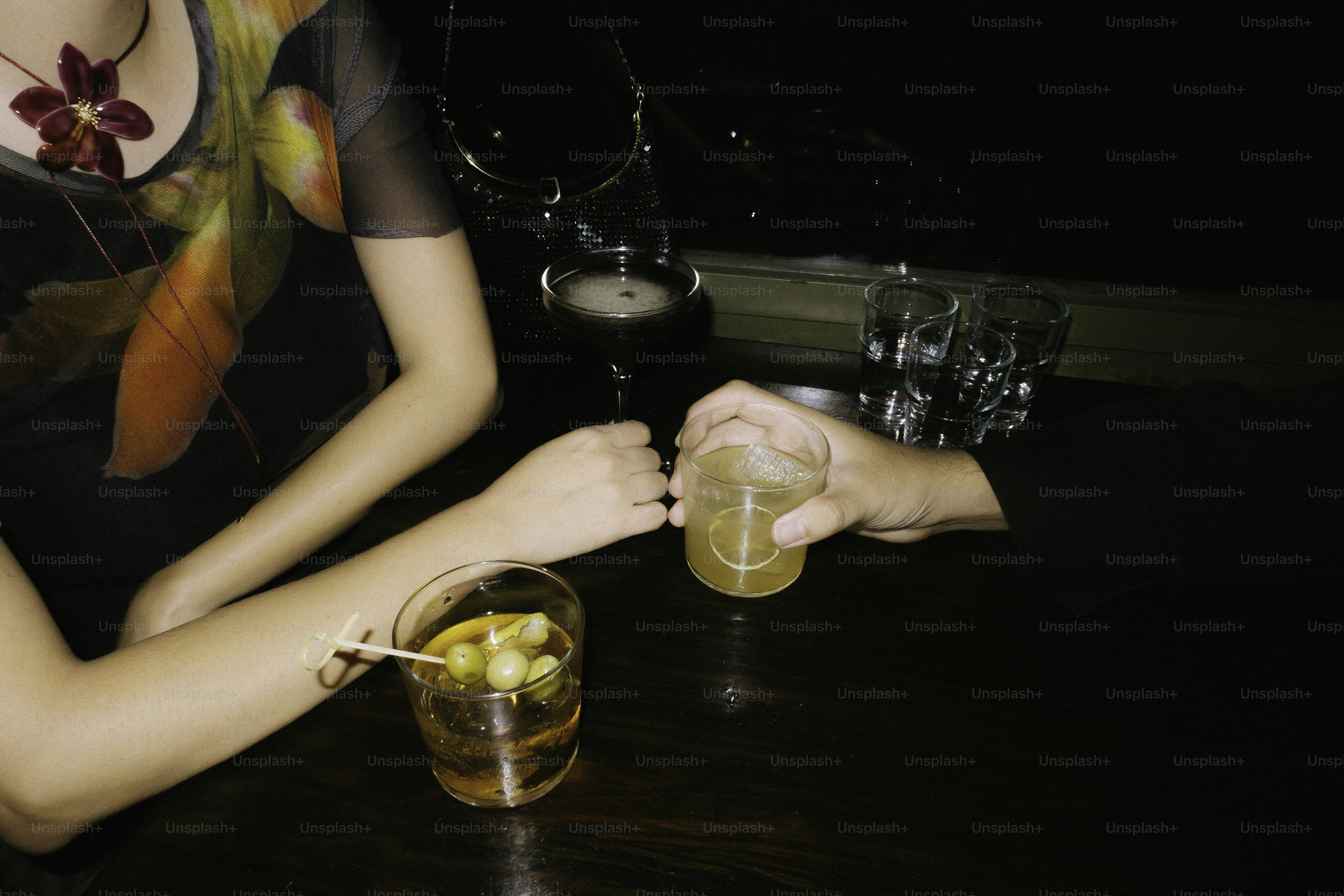 Two people clinking glasses with cocktails