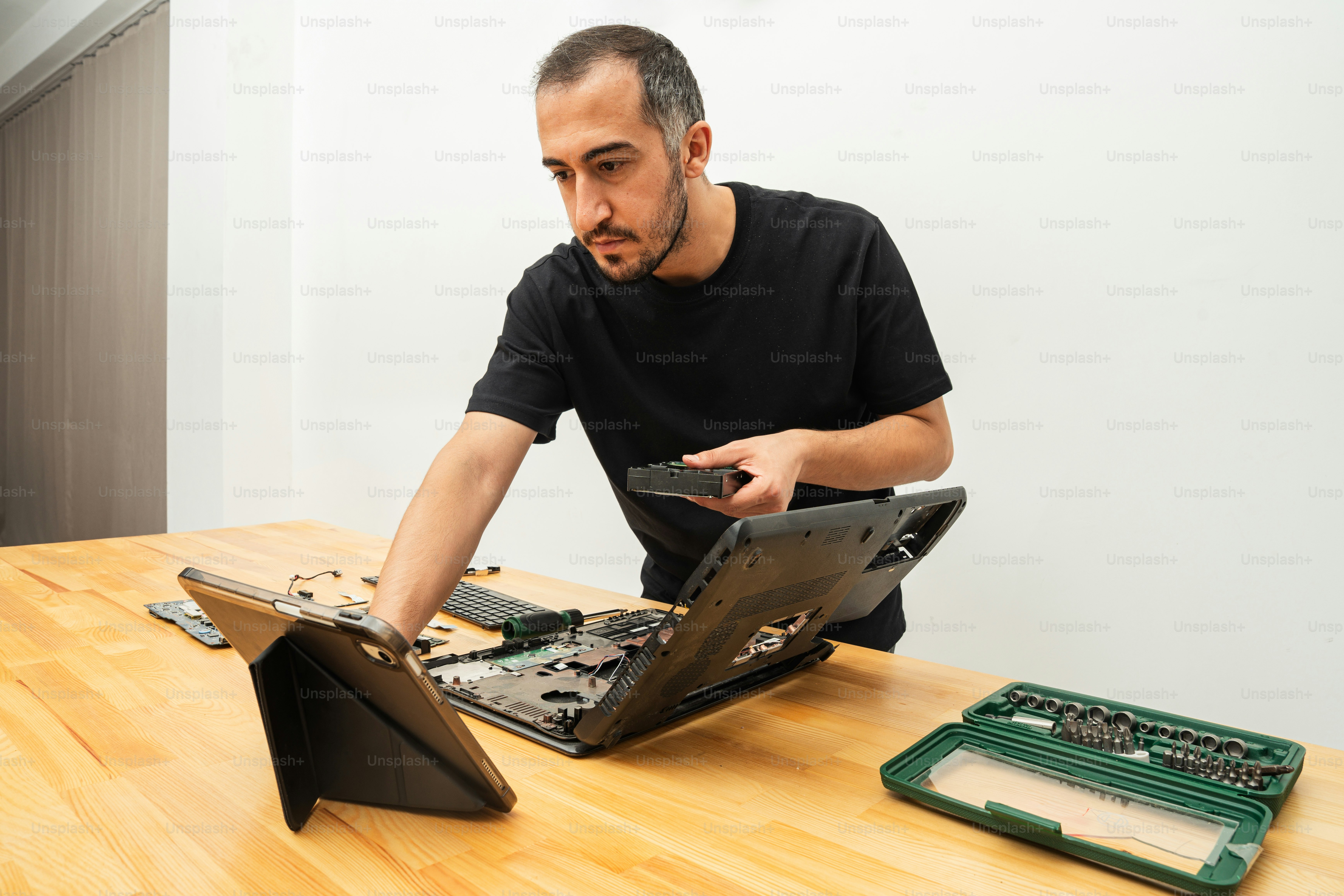Pria membongkar laptop dengan alat di atas meja