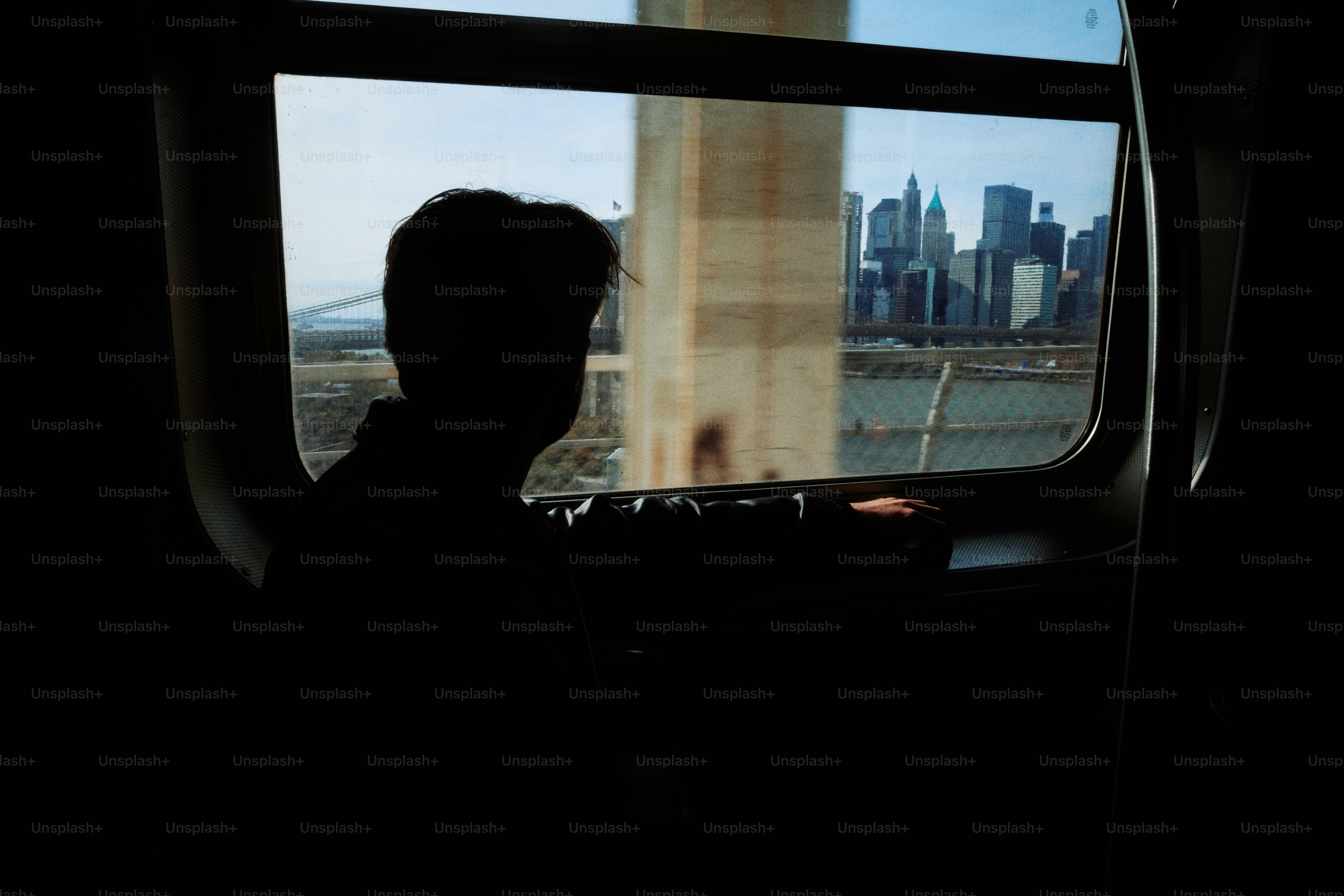 창문 너머로 도시 스카이라인을 바라보는 사람의 실루엣.