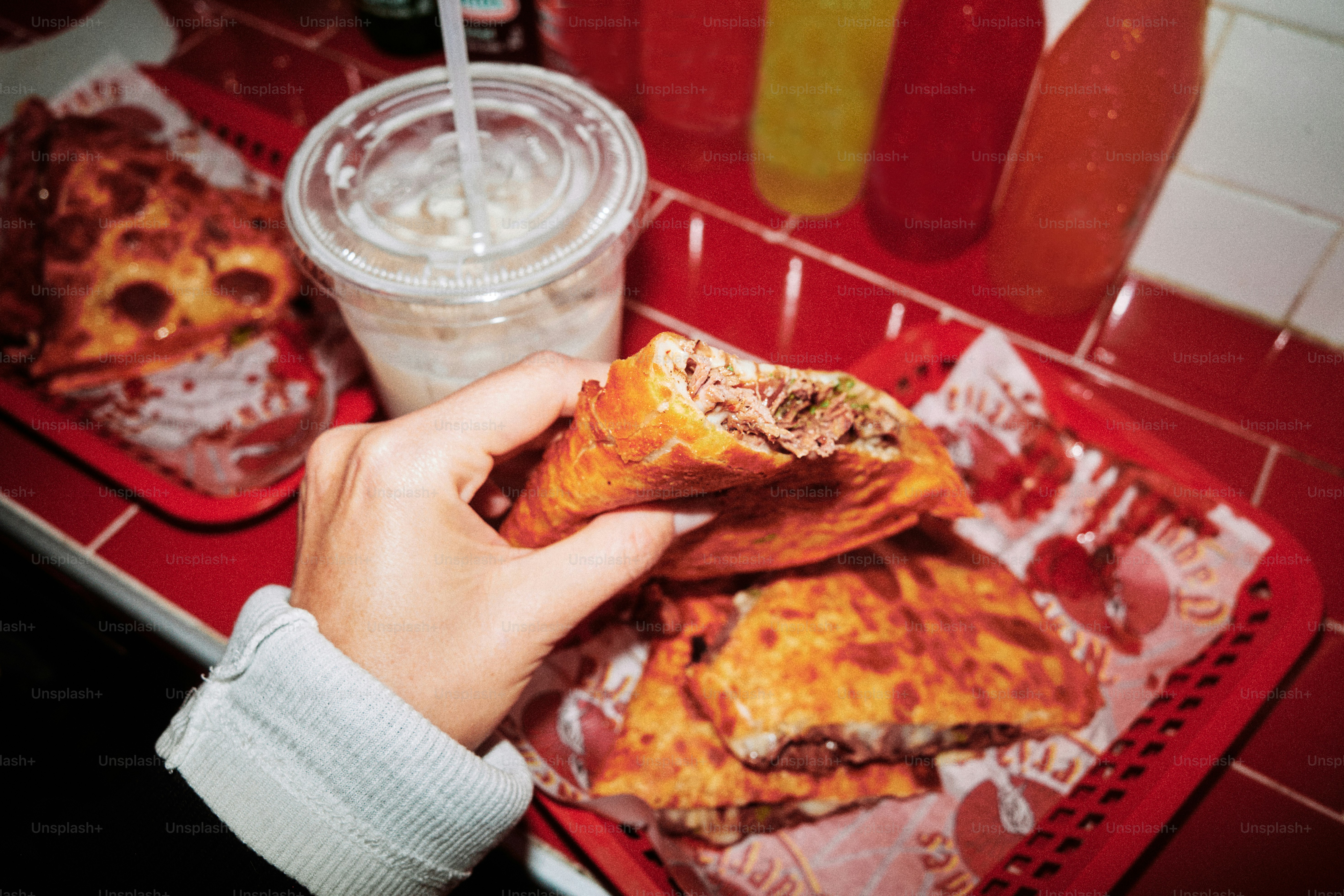 Hand holding a delicious empanada with food tray.