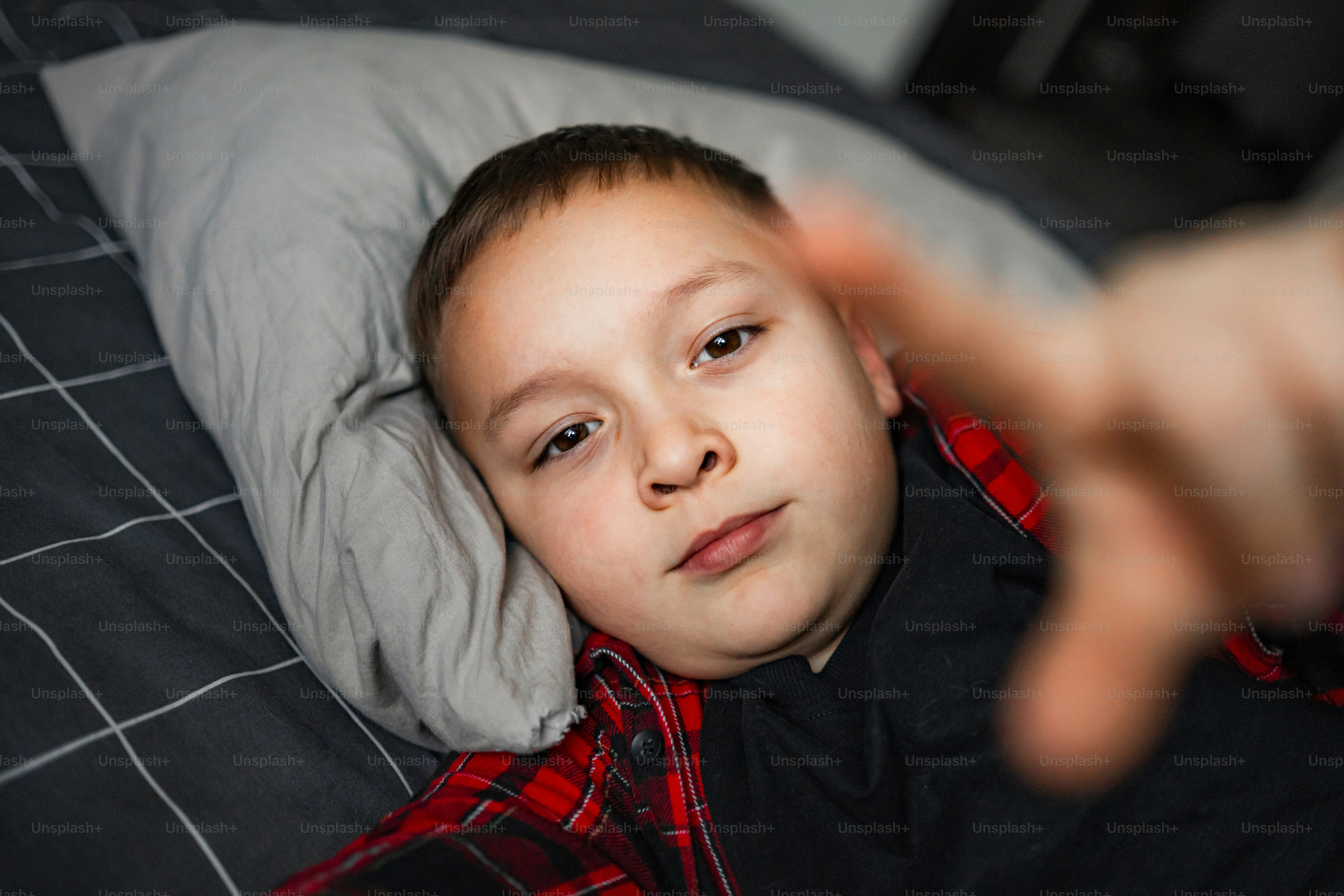 Young boy lying on a pillow, pointing forward.