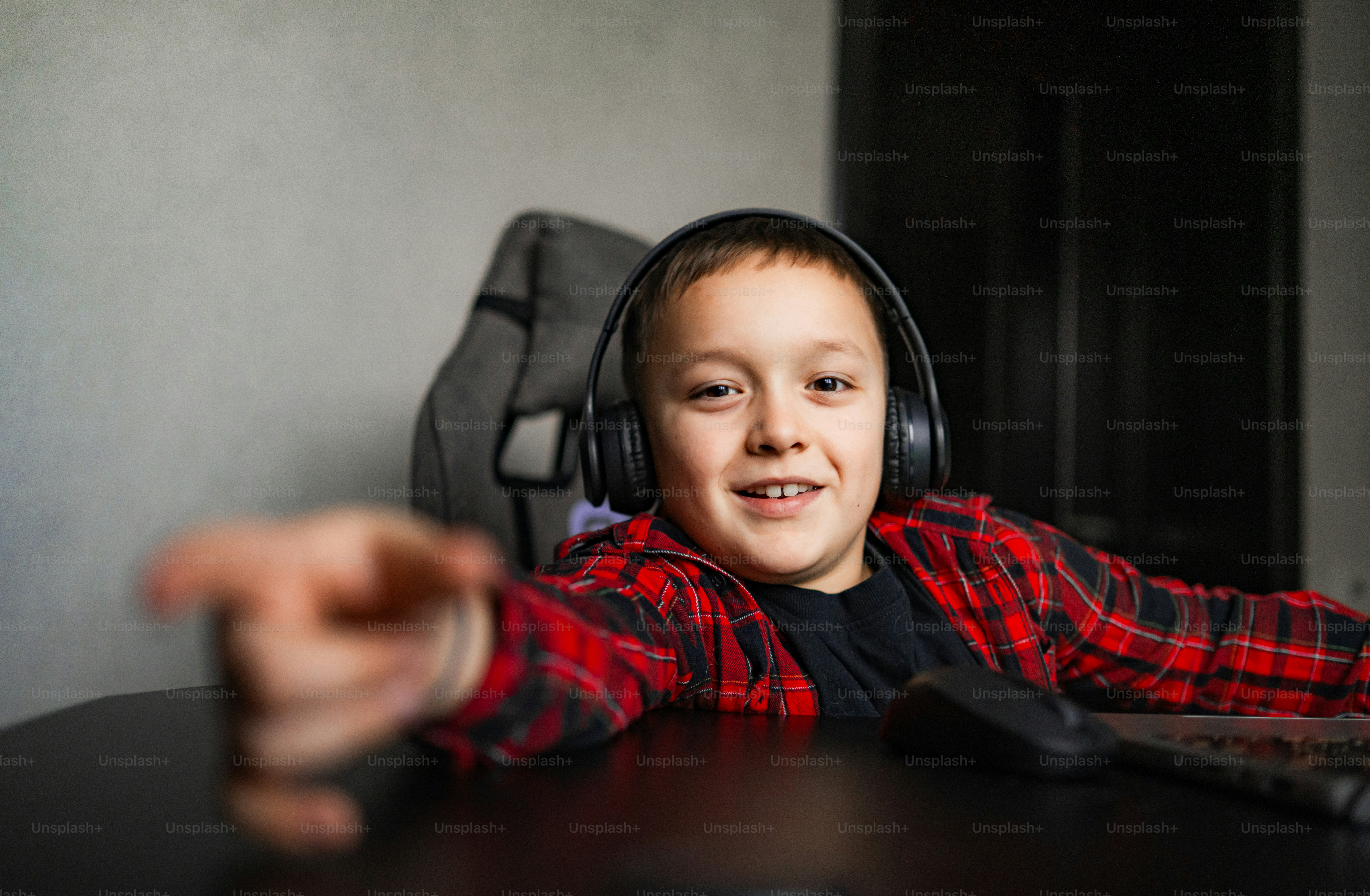 Boy wearing headphones and a red plaid shirt.