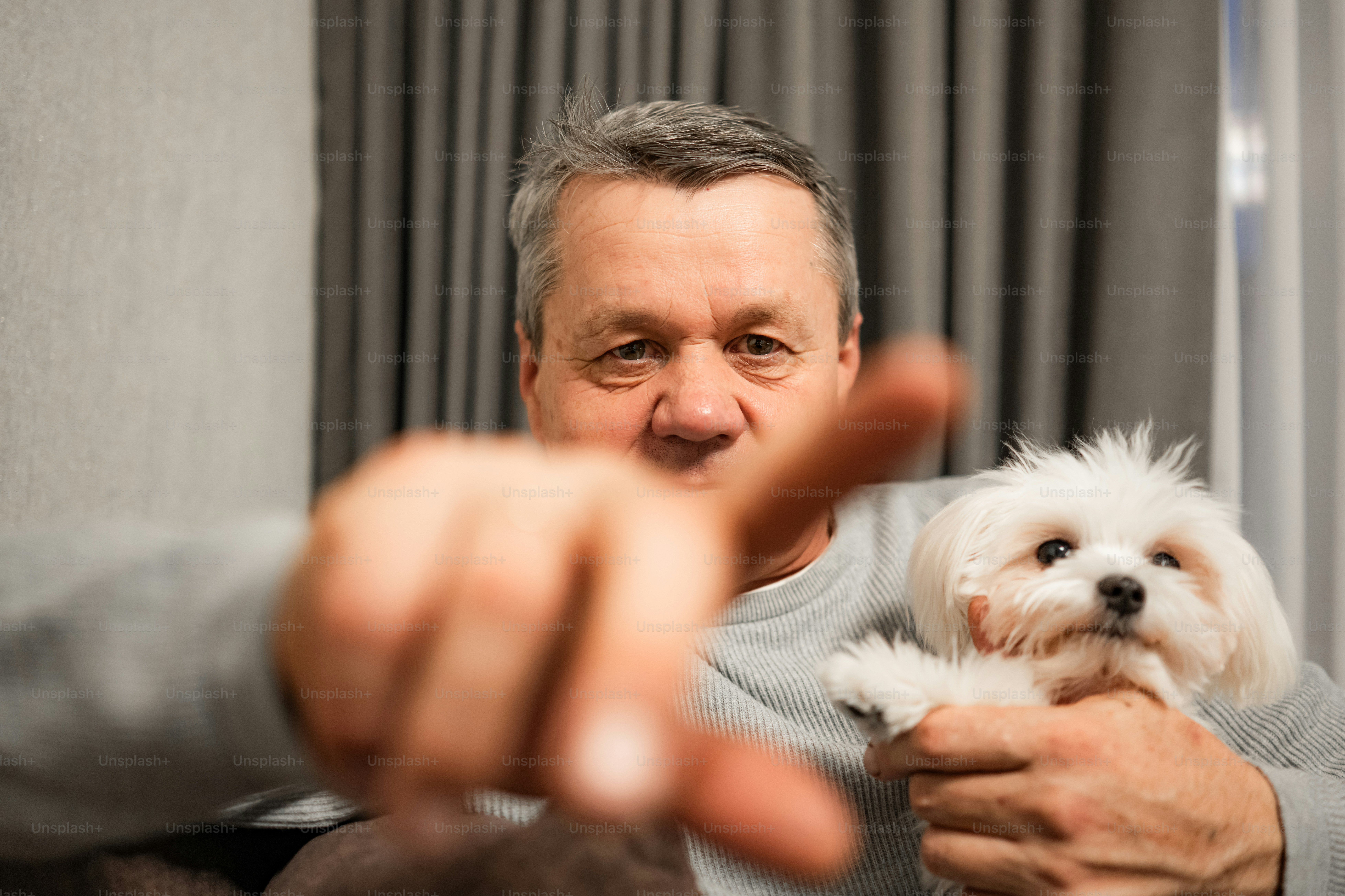 Man holding a small white dog, pointing finger