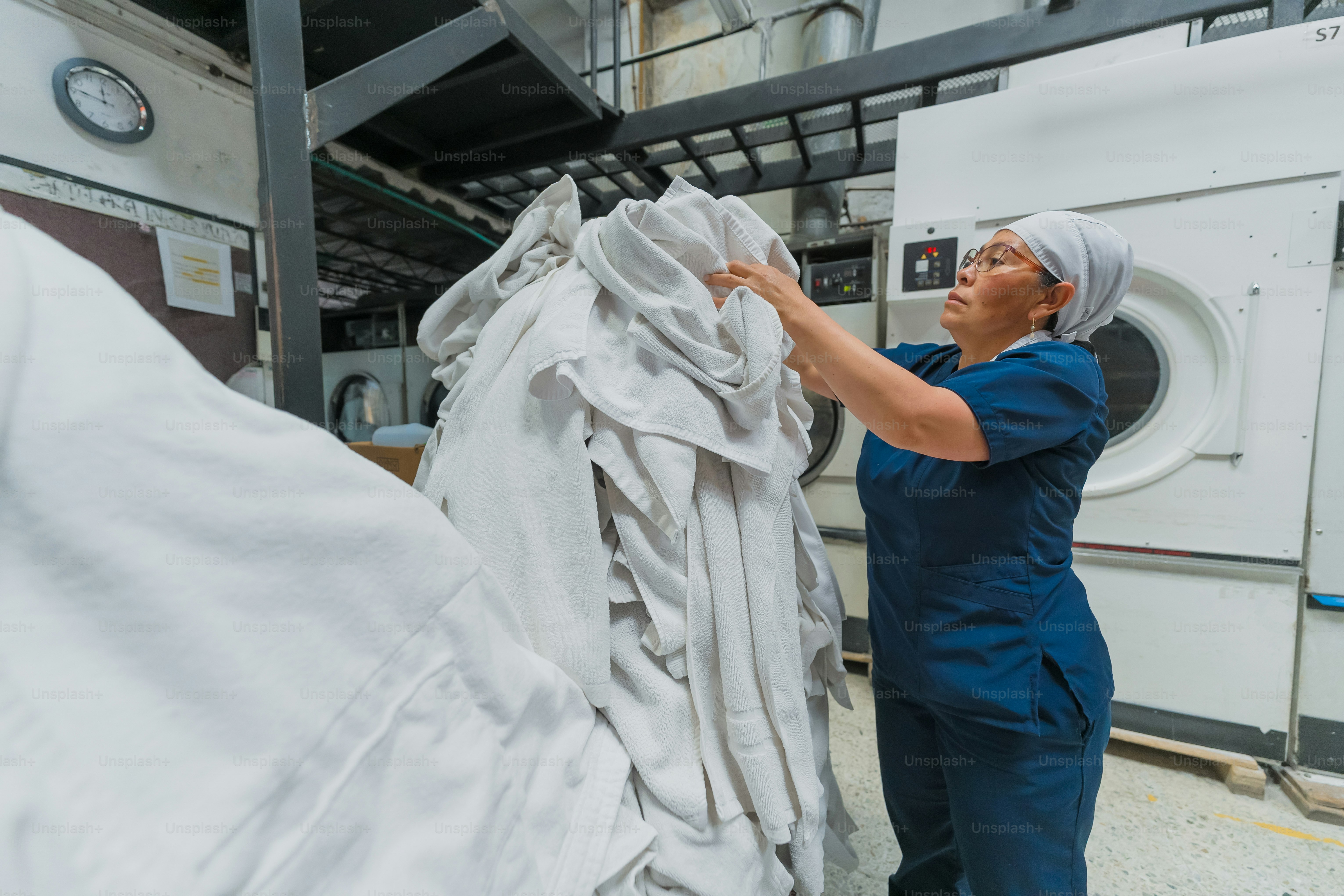 Woman folding large pile of white linens
