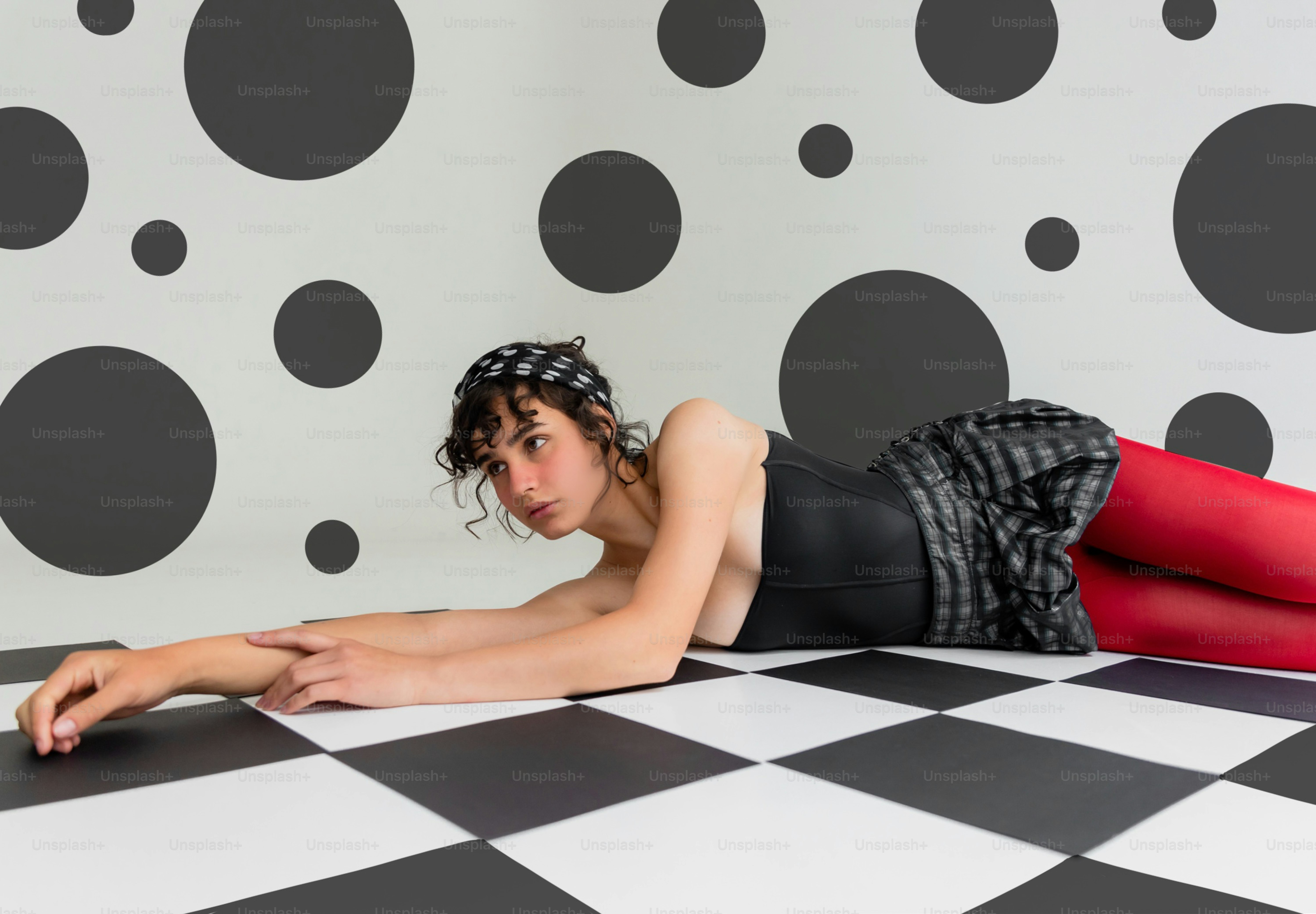 Frau in roten Strumpfhosen liegt auf karierten Boden.