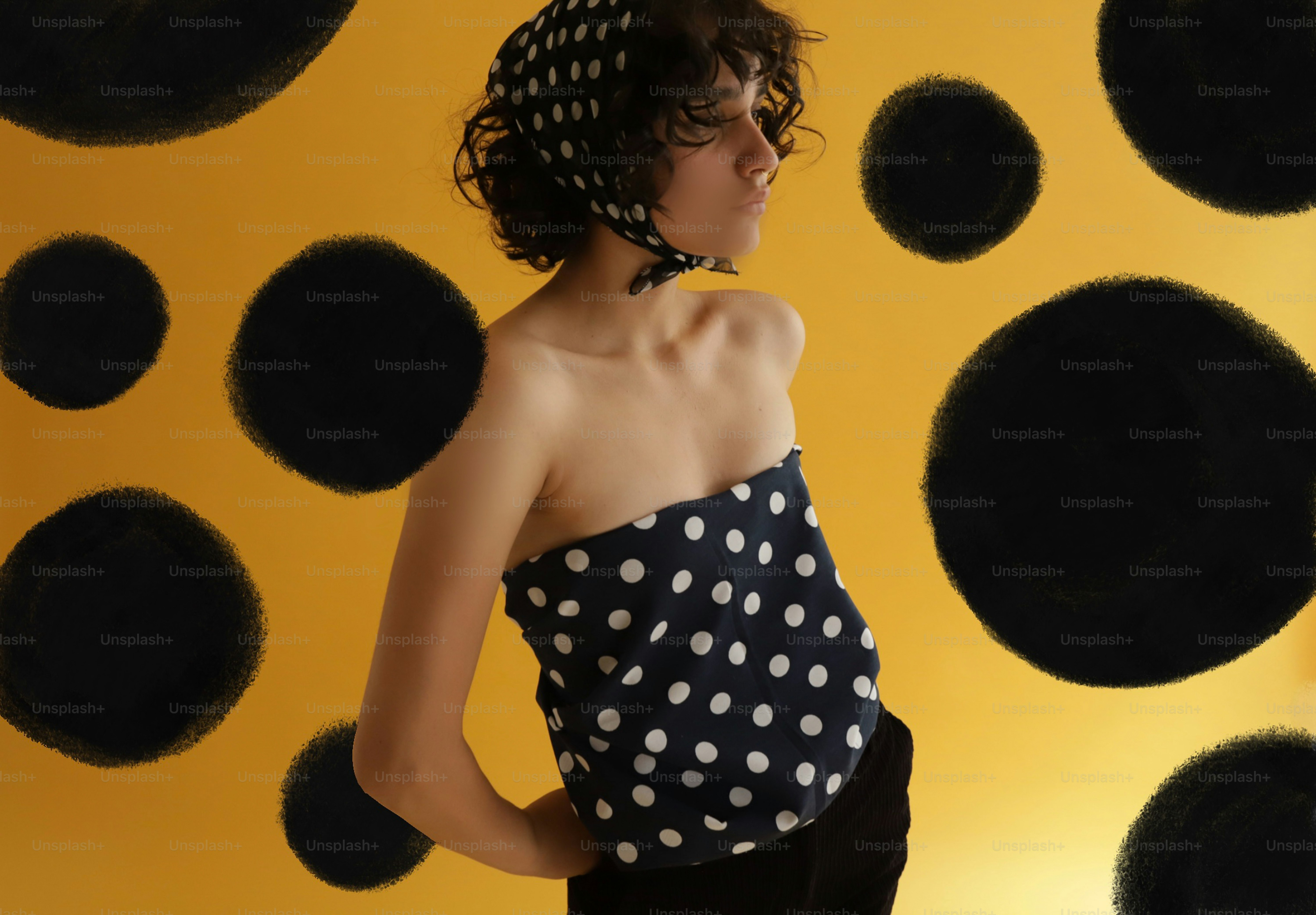 Frau mit gepunktetem Oberteil an der gelben Wand