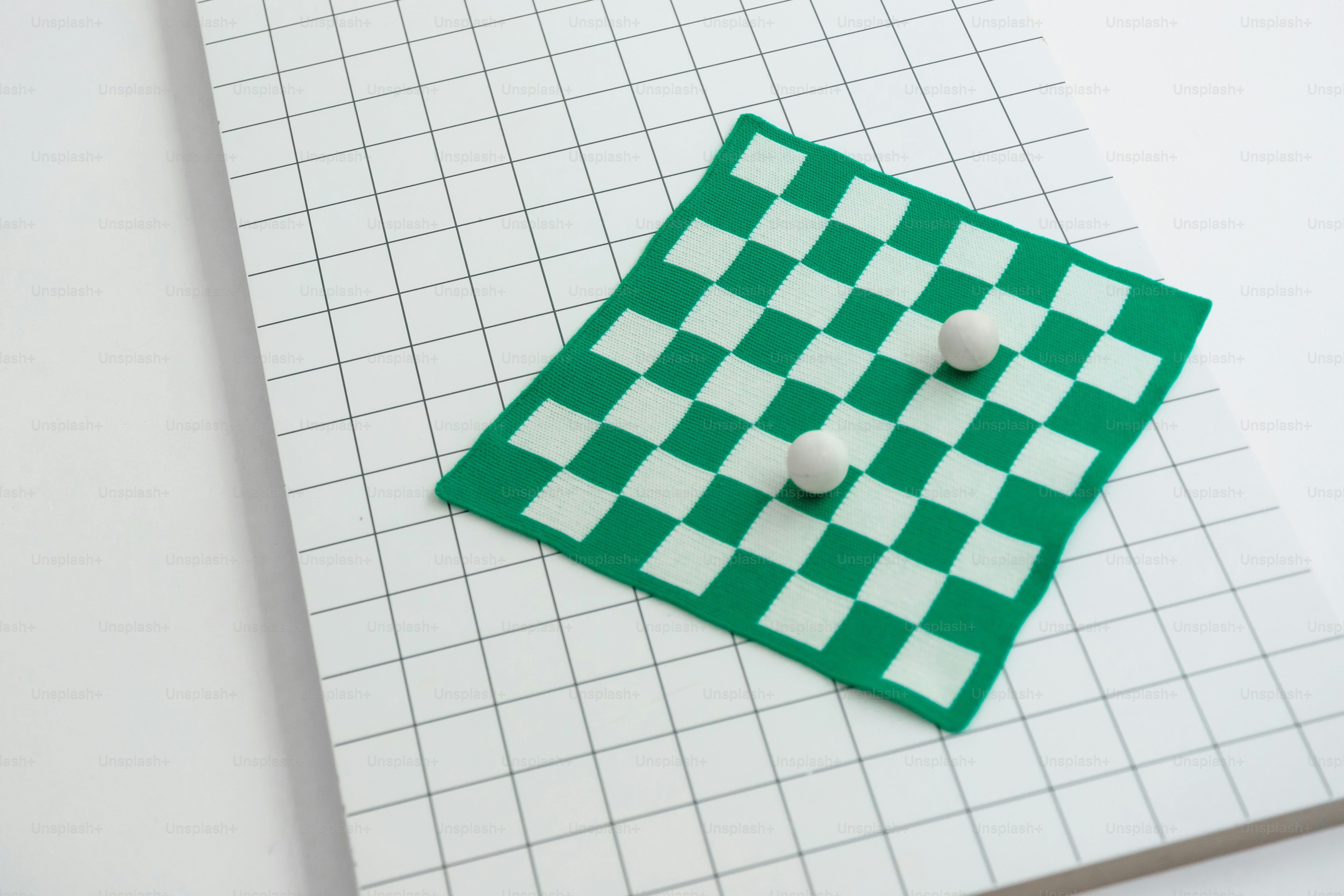 Zwei weiße Kugeln auf einem grünen Schachbrett.