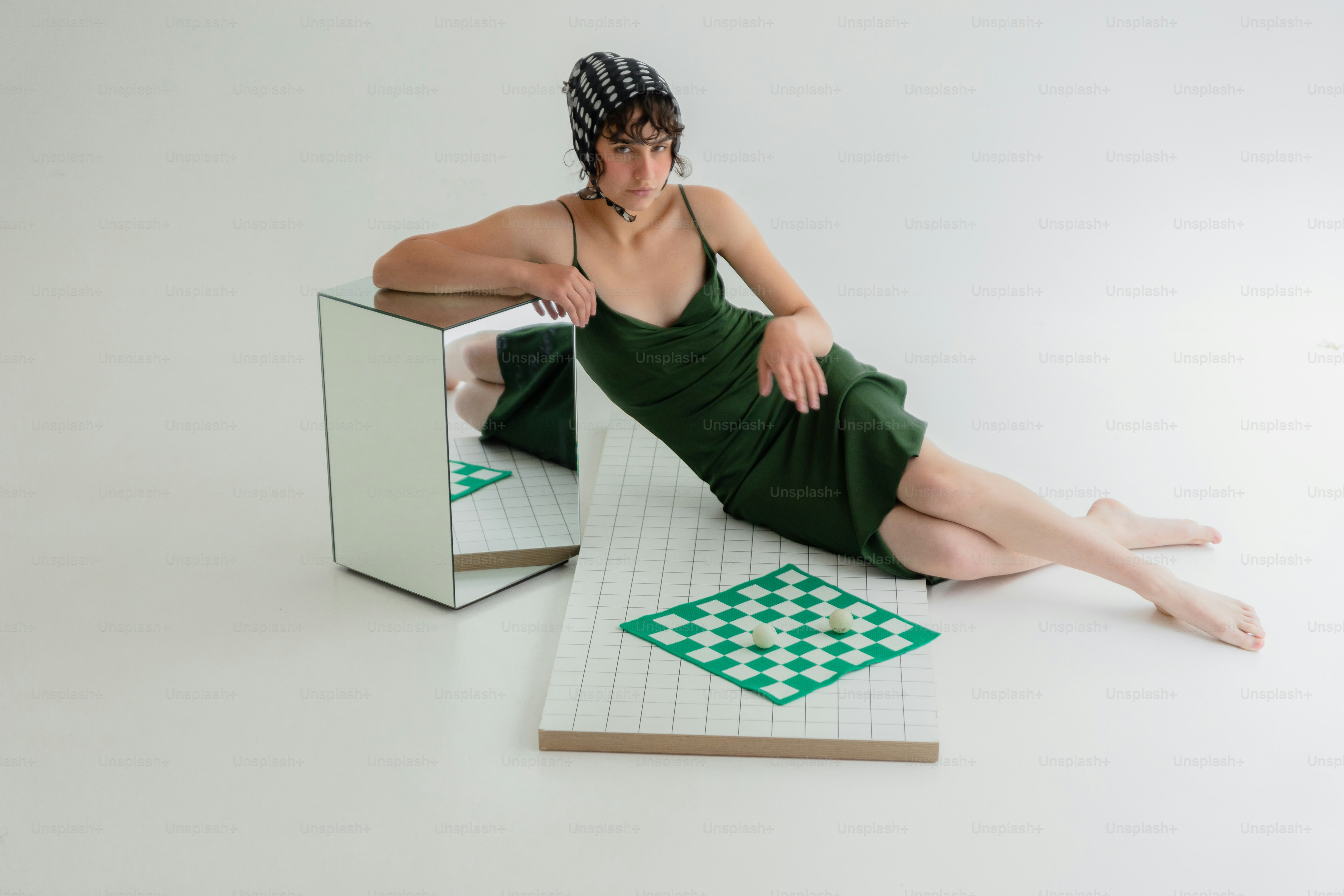 Woman in green dress and striped hat by chessboard